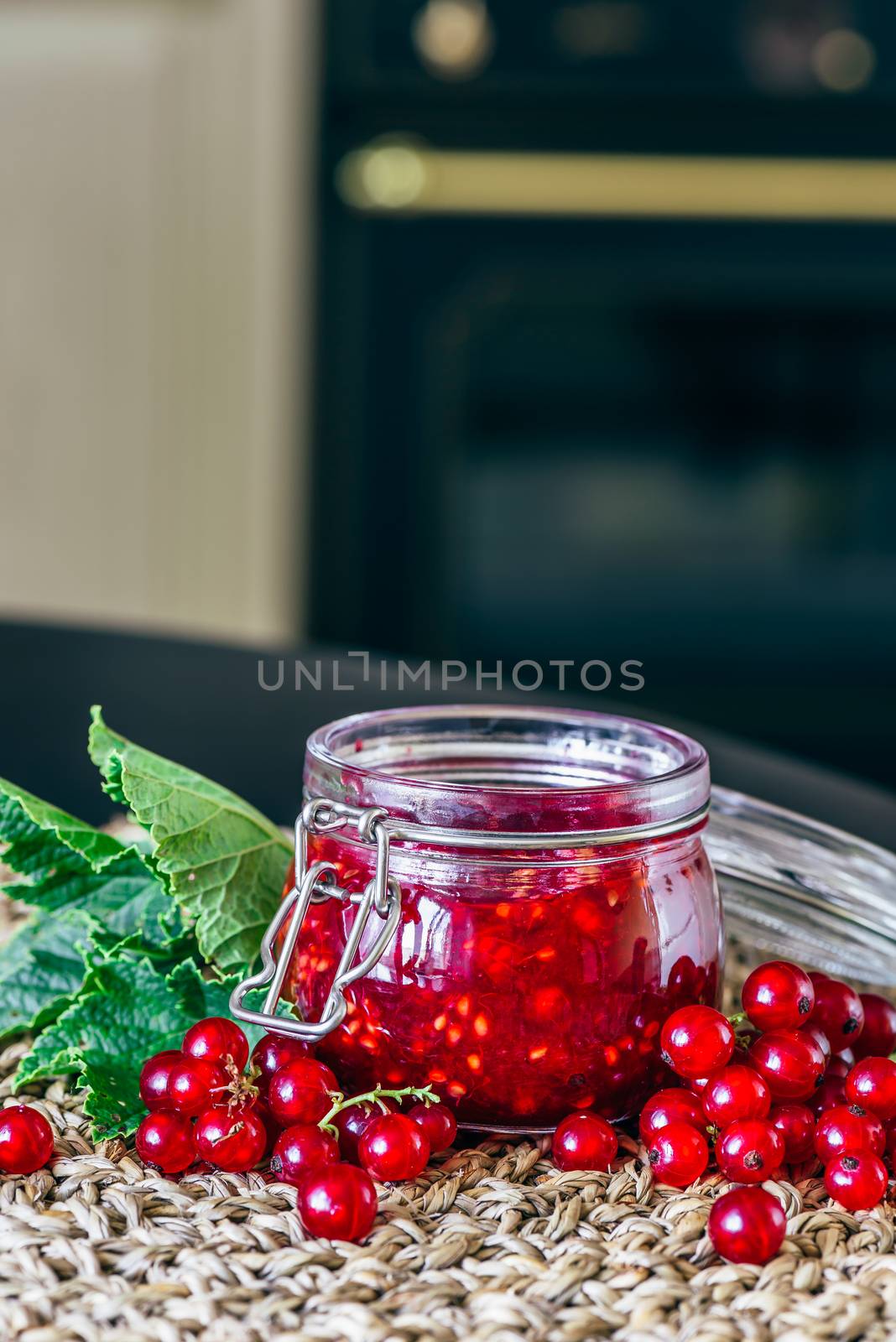Homemade Jam in Glass Jar with Raw Red Currant and Leaves.