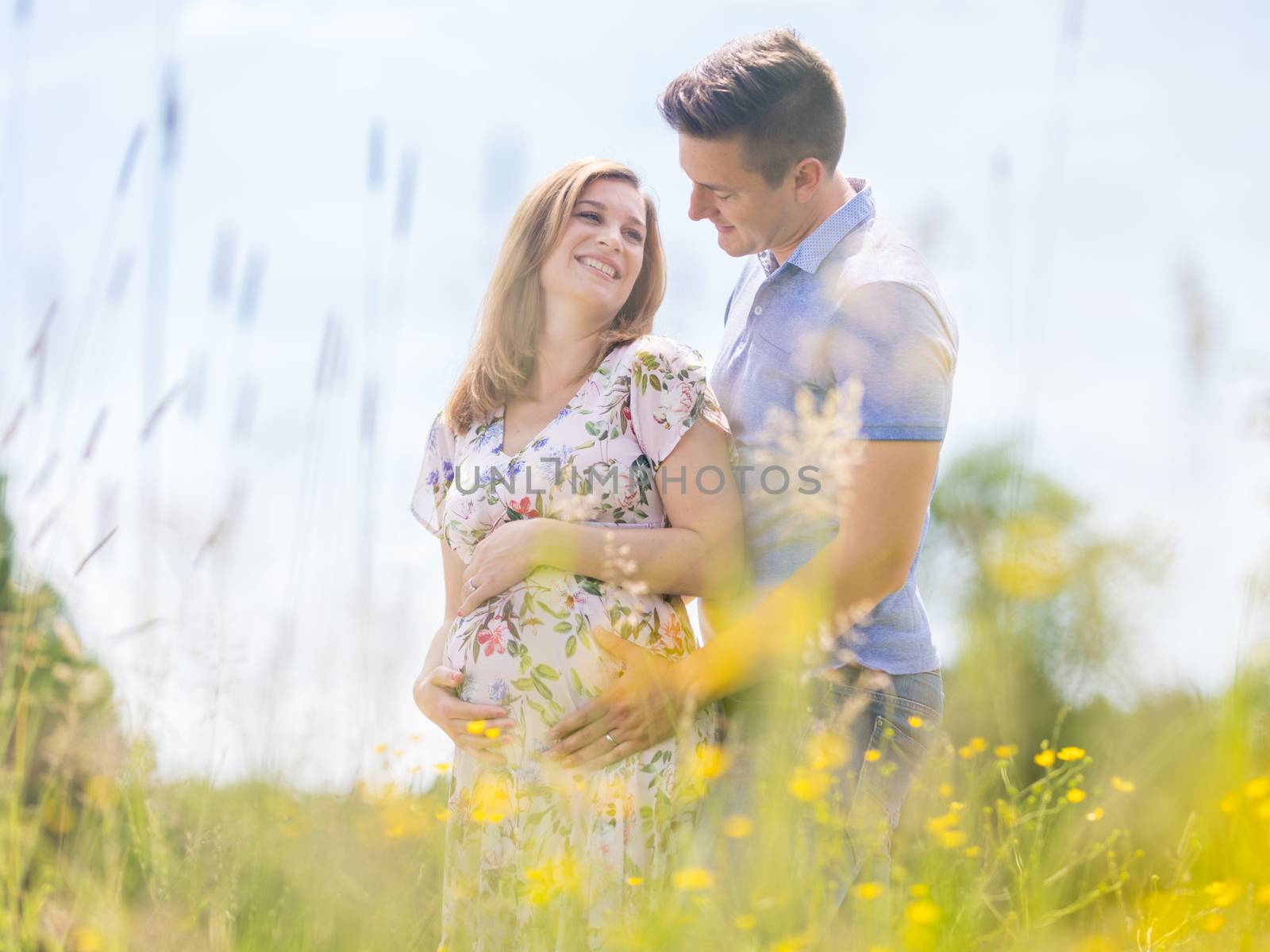 Young happy pregnant couple hugging in nature. Concept of love, relationship, care, marriage, family creation, pregnancy and parenting.