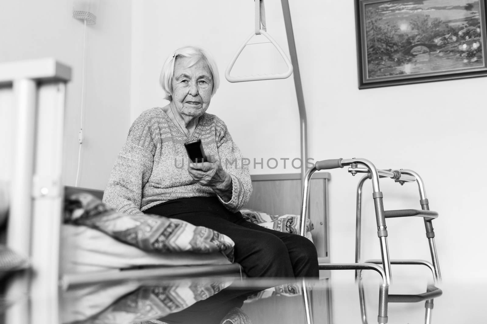 Elderly 96 years old woman operating TV or DVD with remote control. Black and white image.