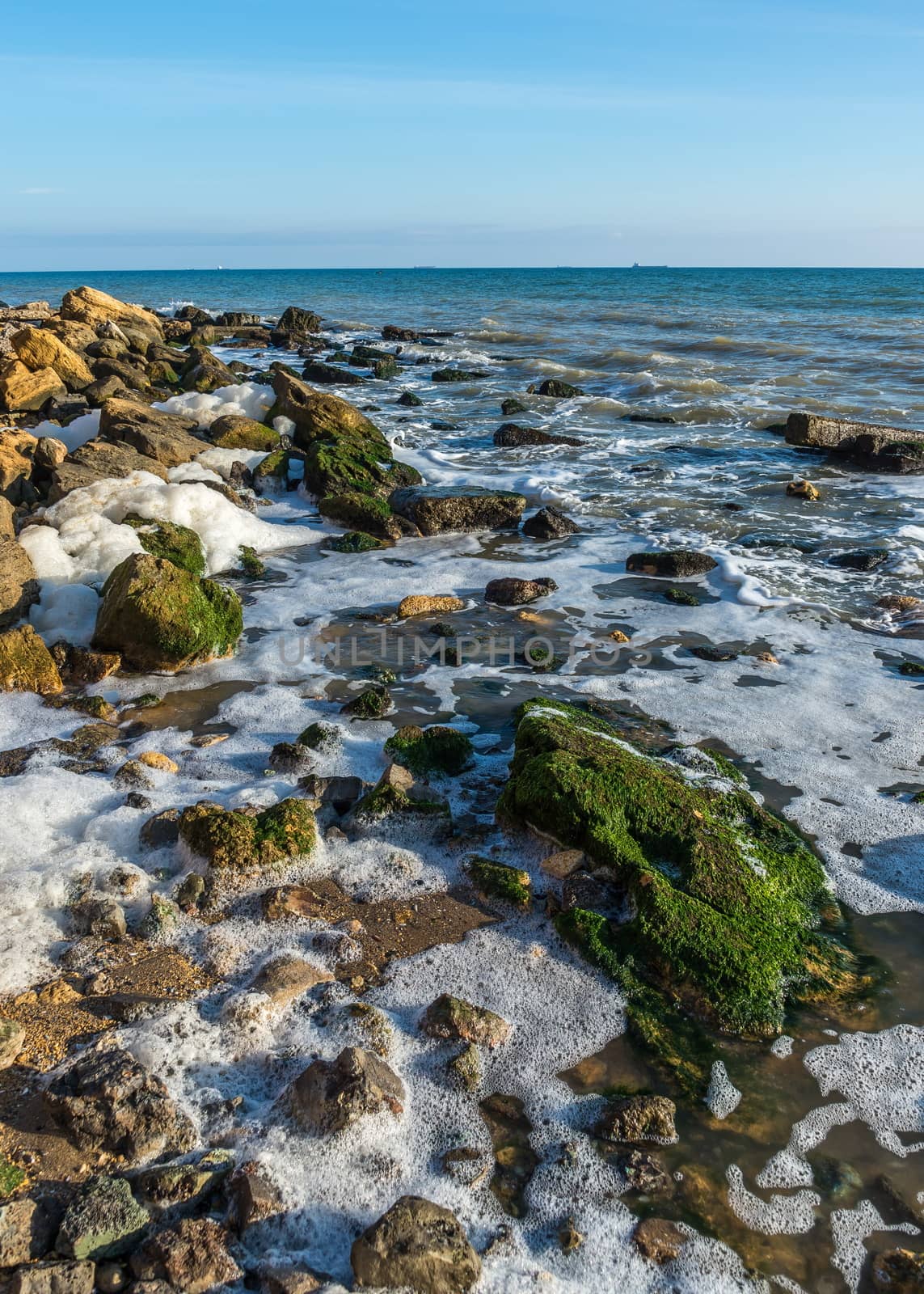 Sea foam and stones on the shore by Multipedia