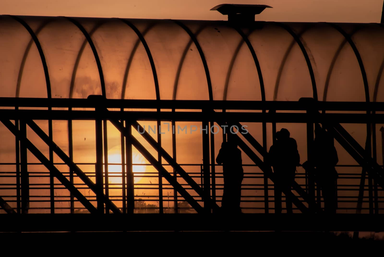 People standing in a walkway by sunset