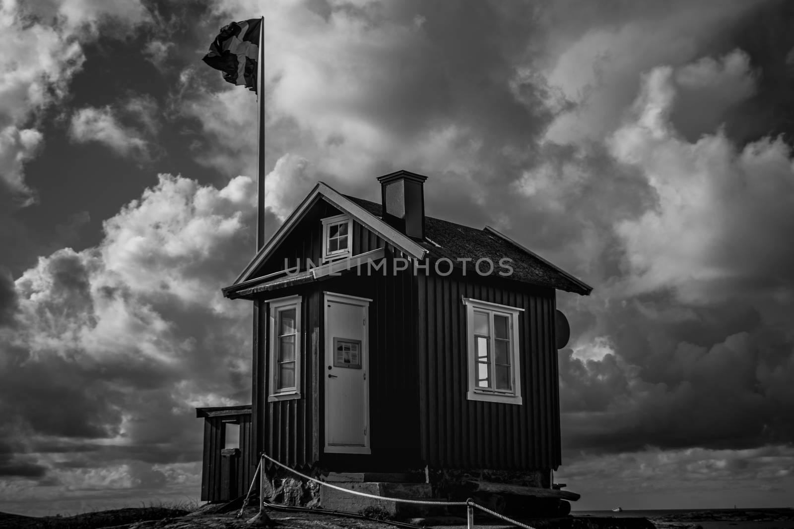 A classic Swedish hut in front of a Swedish flag in the Gothenburg archipelago black and white