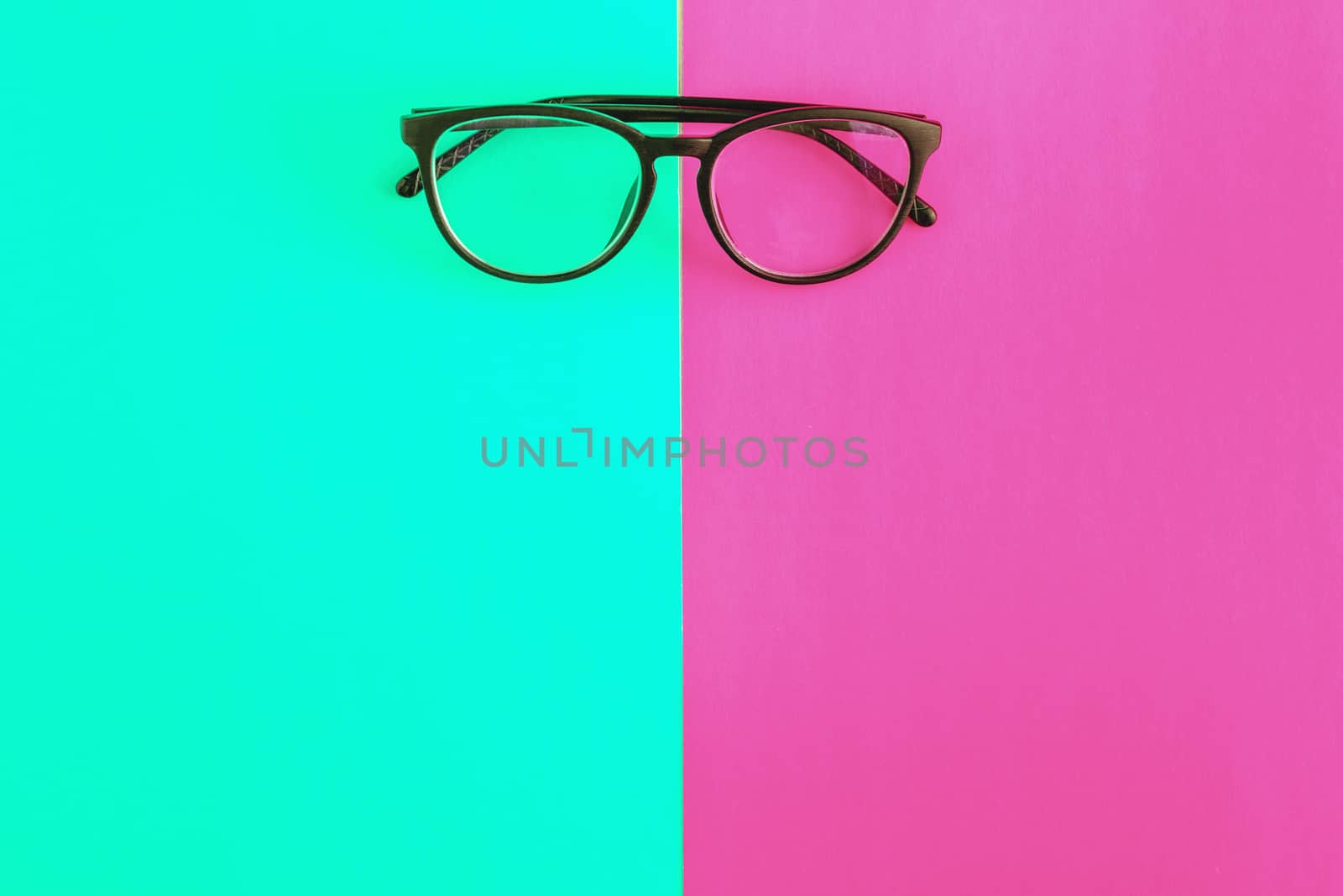 stylish glasses on a bright green-cyan and crimson-pink background, top view, isolated. Copy space. Flat lay.