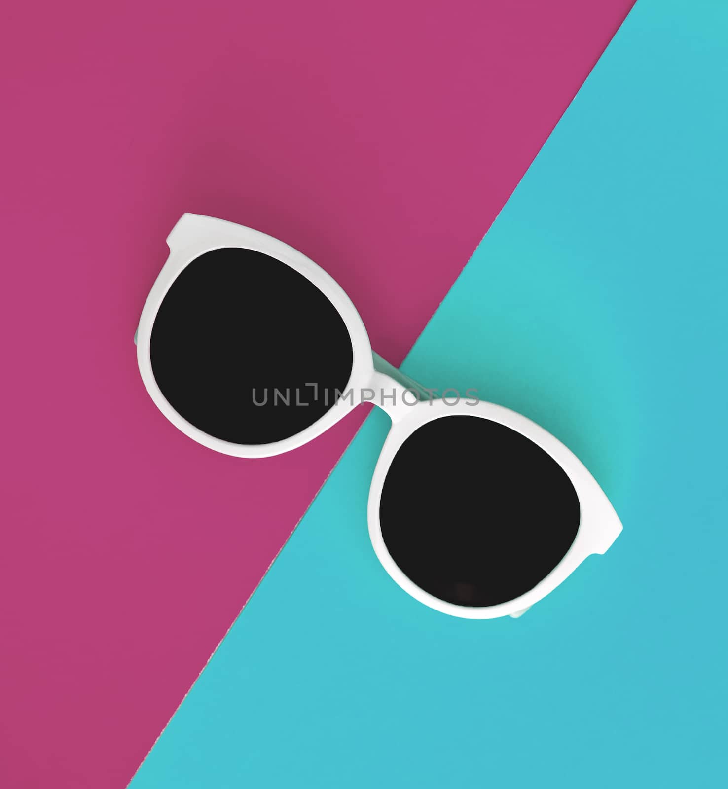 Sunny stylish white sunglasses on a bright green-cyan and crimson-pink background, top view, isolated. Copy space. Flat lay.