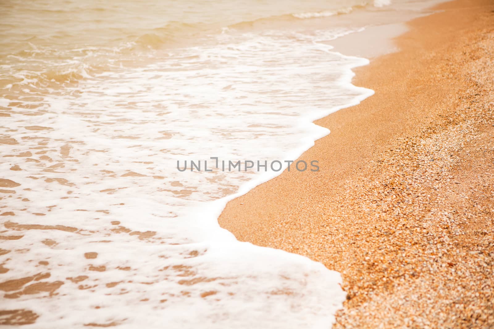 Atmospheric, melancholic mood, blurred background with copy space. View of shell beach and sea foaming waves. For design mockup, screensaver for device, content for social media. Horizontal