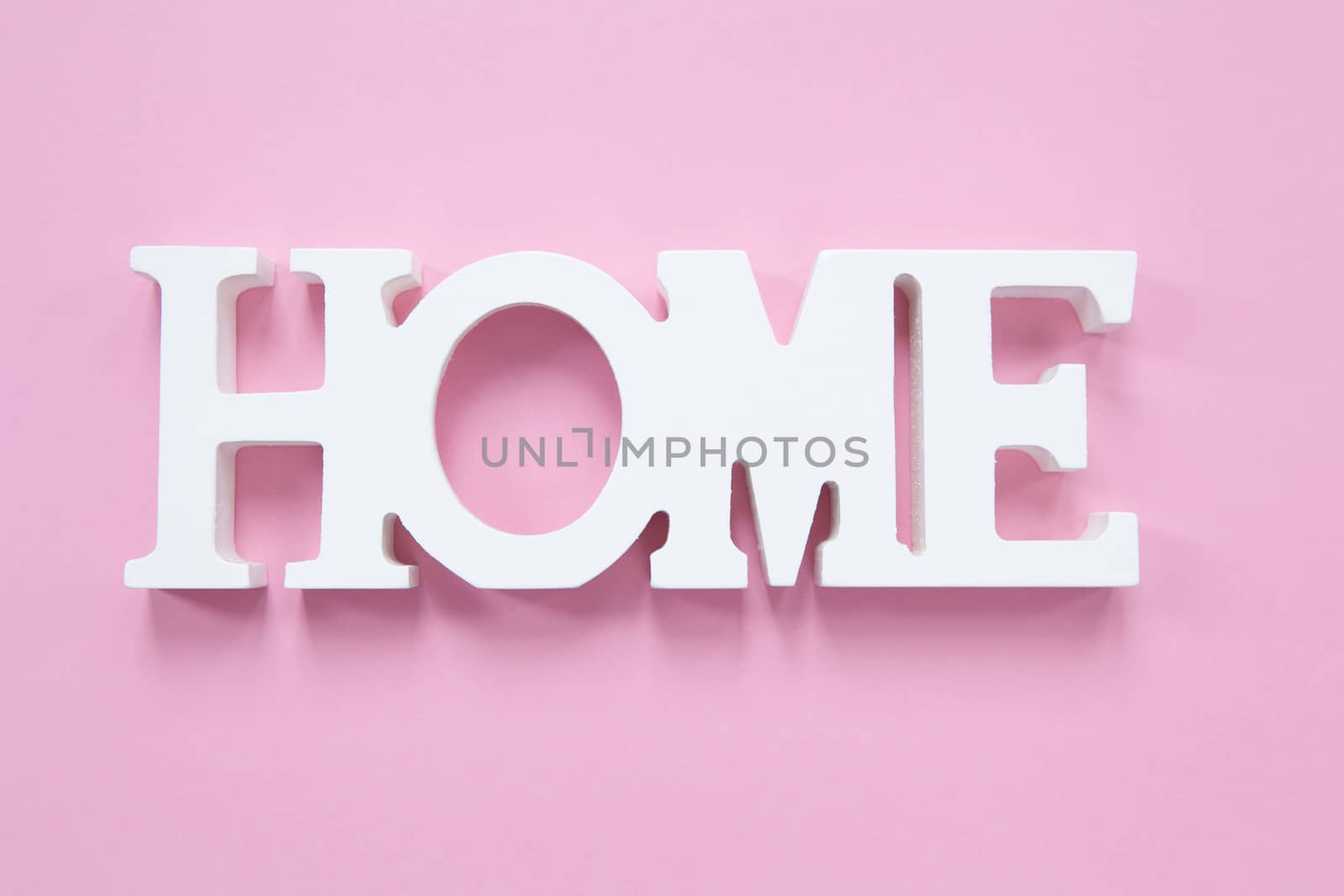 Decorative wooden word Home on a millennial pink background. Concept of home comfort, romance. Horizontal format. Flat lay