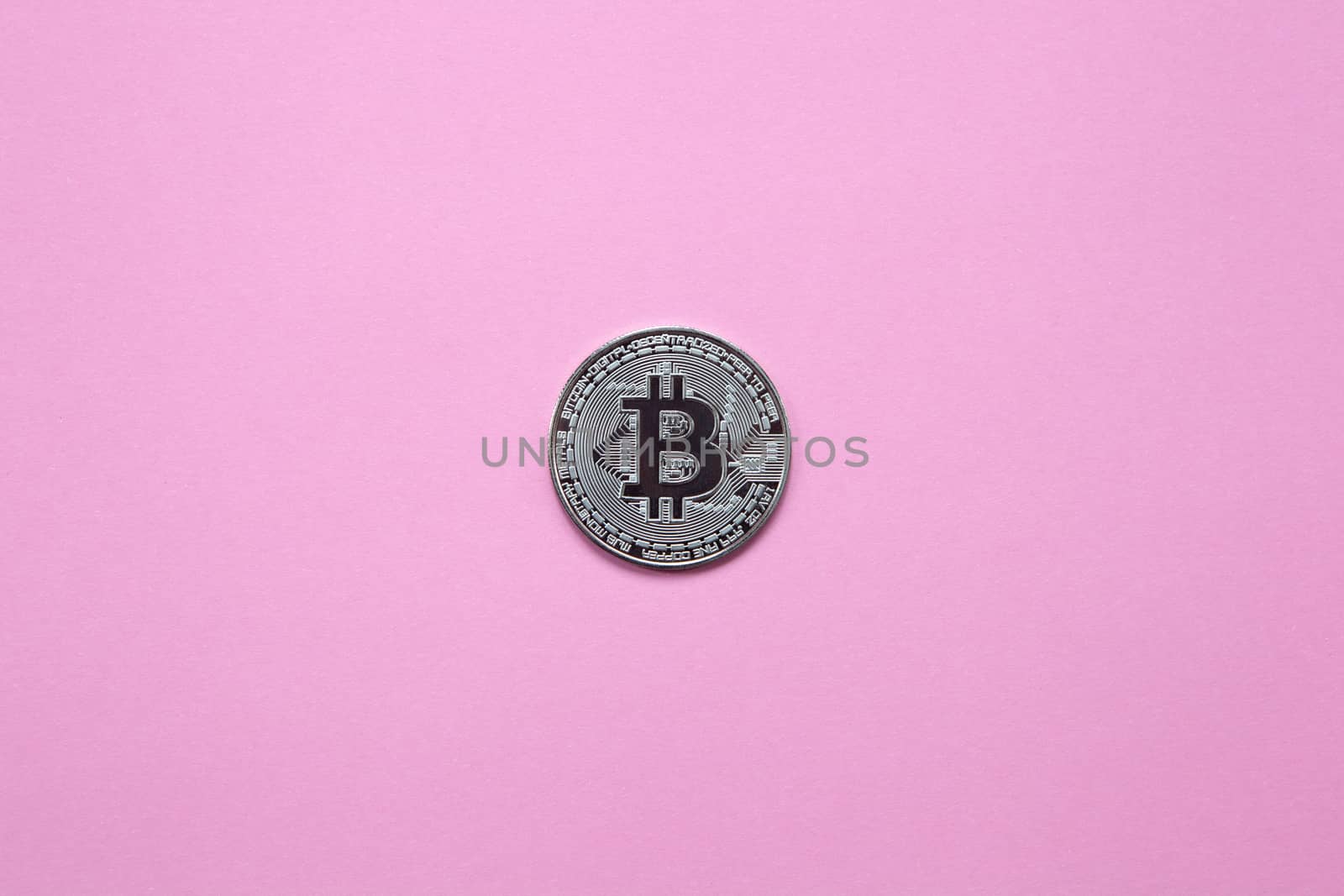 Silver bitcoin on a millennial pink background. Top view. Minimalism. Horizontal orientation.
