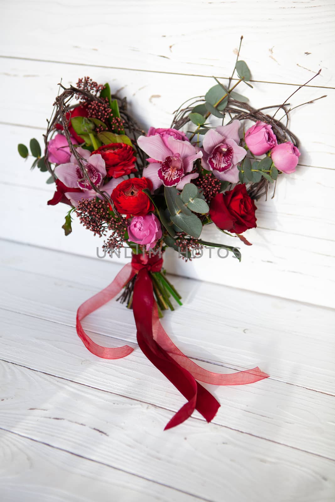 Unusual creative bouquet of flowers in the shape of heart on white wooden background. Card for Valentine's day. Flower delivery, wedding agencies. Mother's day, 8 March, Happy Women's Day