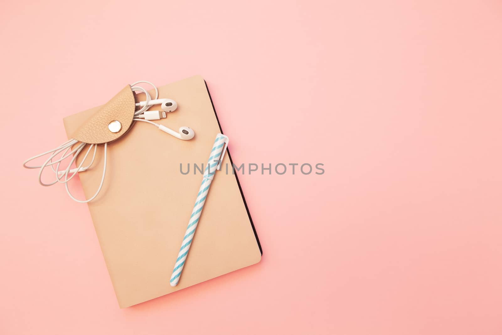 Beige diary with blue pen and headphones on pastel millennial pink paper background. Concept of education, blogging. Top view. Flat lay. Minimal style. Template for female blog. Lifestyle. Copy space.