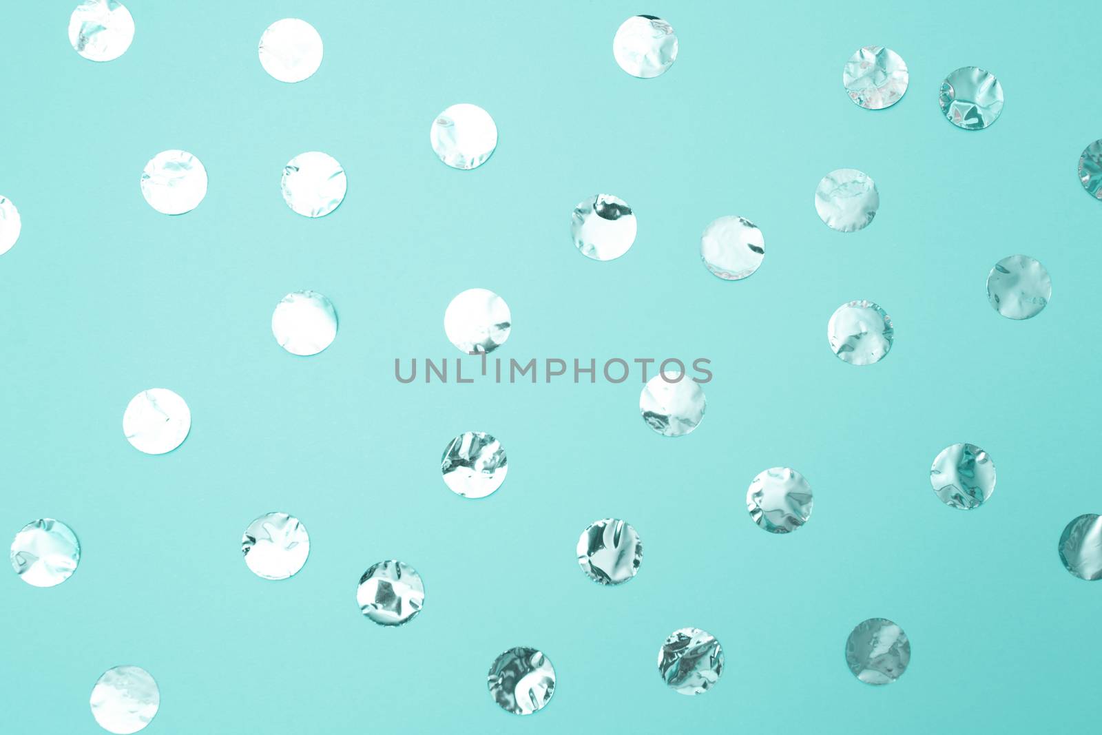 Pattern of shiny silver confetti on pastel turquoise paper background. Concept of holiday, birthday, blogging, beauty. Top view. Flat lay. Minimal style mock up. Template for blog. Copy space.