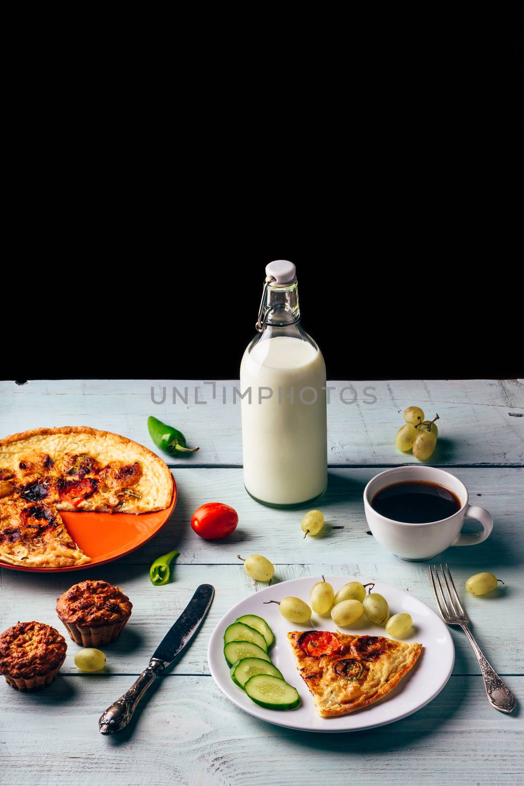 Healthy breakfast with frittata, fruits, vegetables, milk, cup of coffee and muffins on light wooden background.