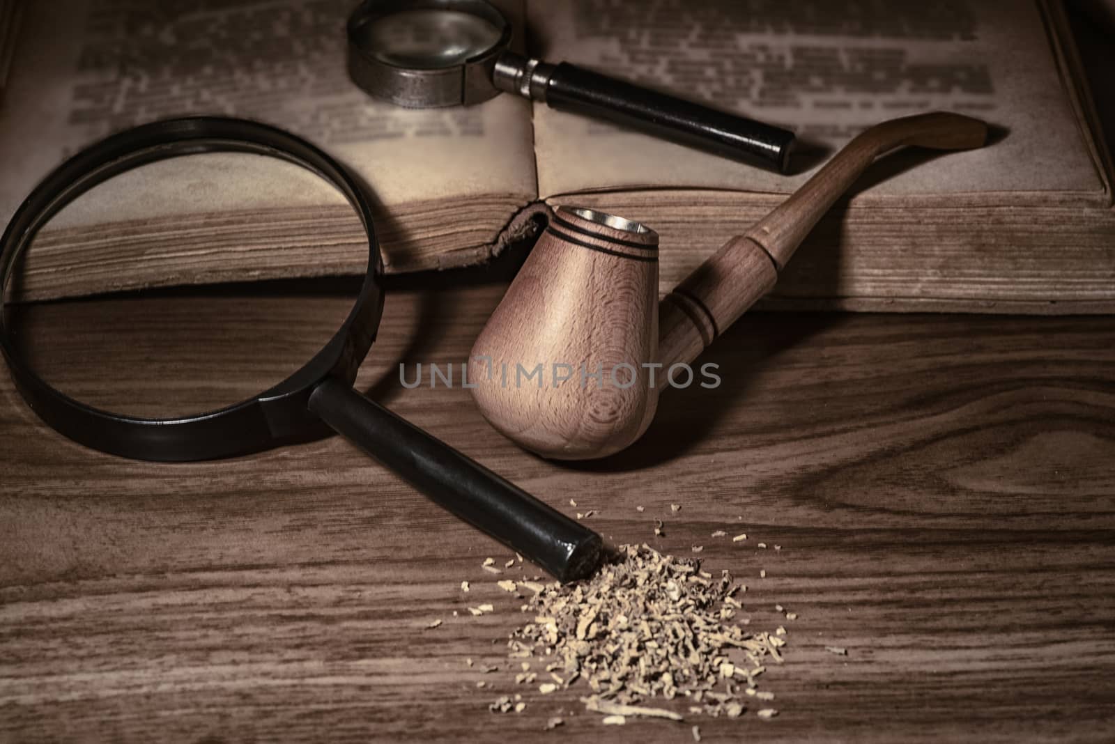 Smoking pipe with tobacco leaves on wooden background.wooden background.Wooden pipe with smoke on heap of chopped dried tobacco leaves against black background.