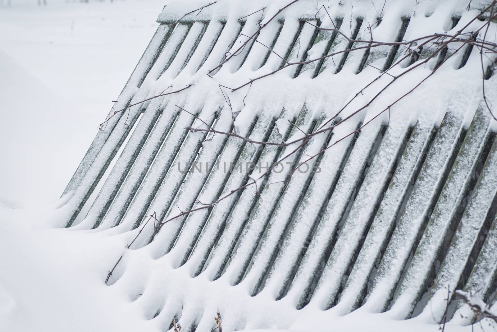 Winter landscape. Season winter. The wooden fence is noticeable with snow.