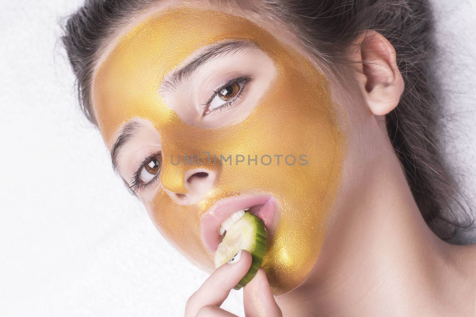 Beautiful girl with a cosmetic mask on the face of golden color. Beautiful model removing golden facial skin cosmetic. Beauty skincare .Close-up. Free space. Woman gold mask. .
