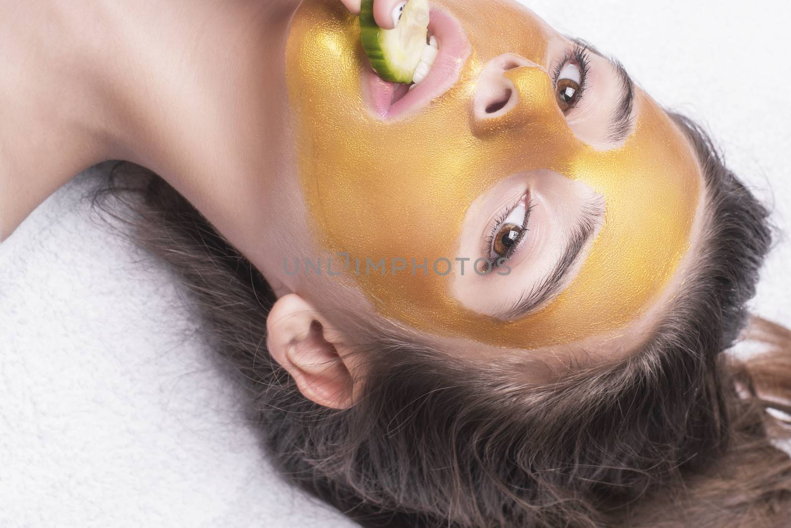 Beautiful girl with a cosmetic mask on the face of golden color. Beautiful model removing golden facial skin cosmetic. Beauty skincare .Close-up. Free space. Woman gold mask. .