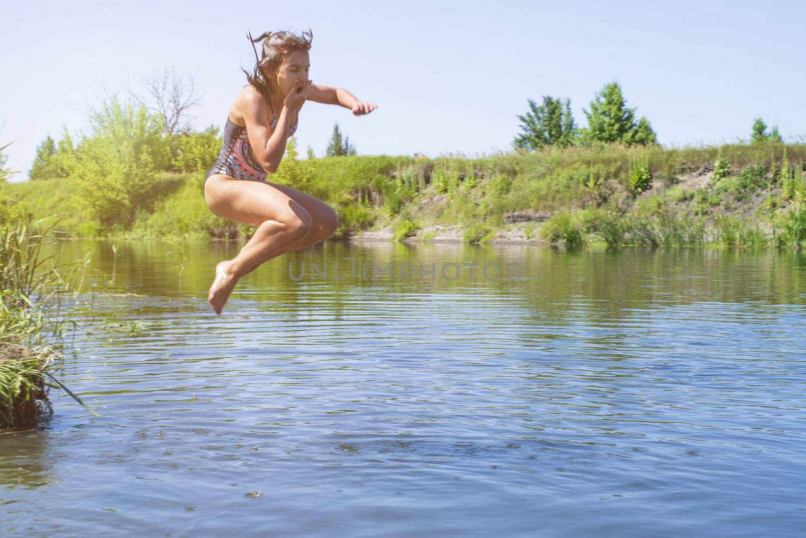little girl running through the water with a splash . in her hands cloth.