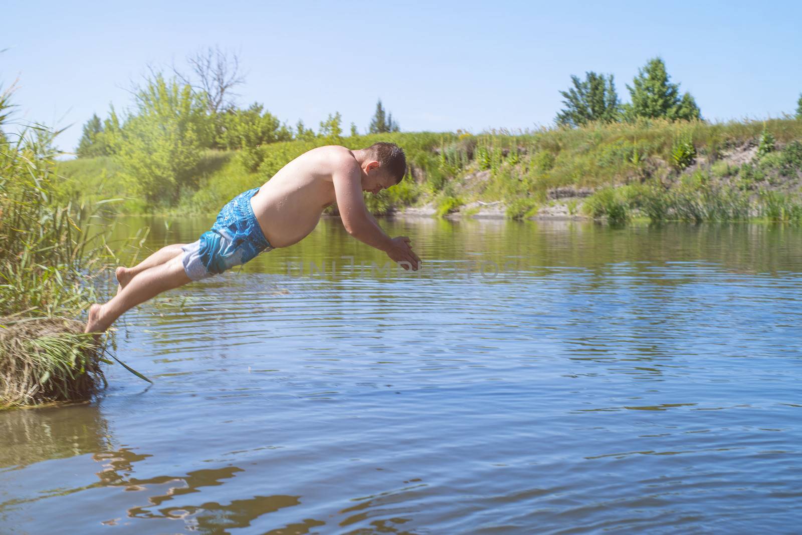 ?an jumps like fish into the water of the lake, swims, enjoys spending time on summer holidaysA fat man jumping on a summer day into a river with a run up.