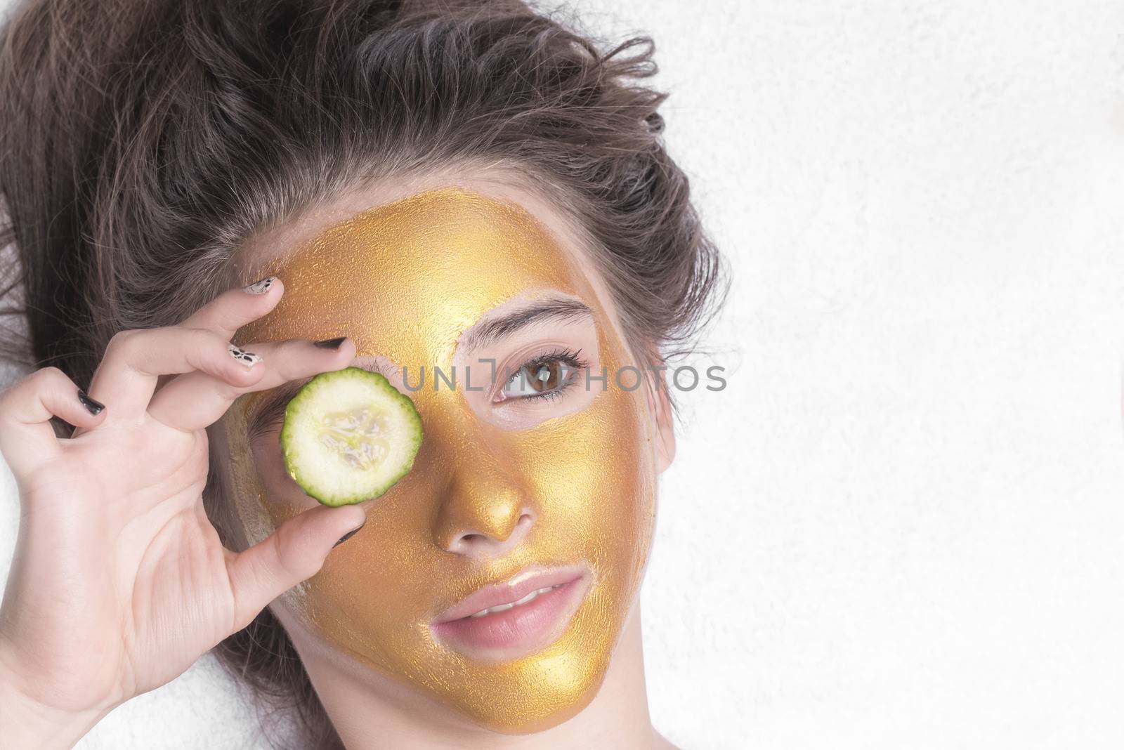 Beautiful girl with a cosmetic mask on the face of golden color. Beautiful model removing golden facial skin cosmetic. Beauty skincare .Close-up. Free space. Woman gold mask. .