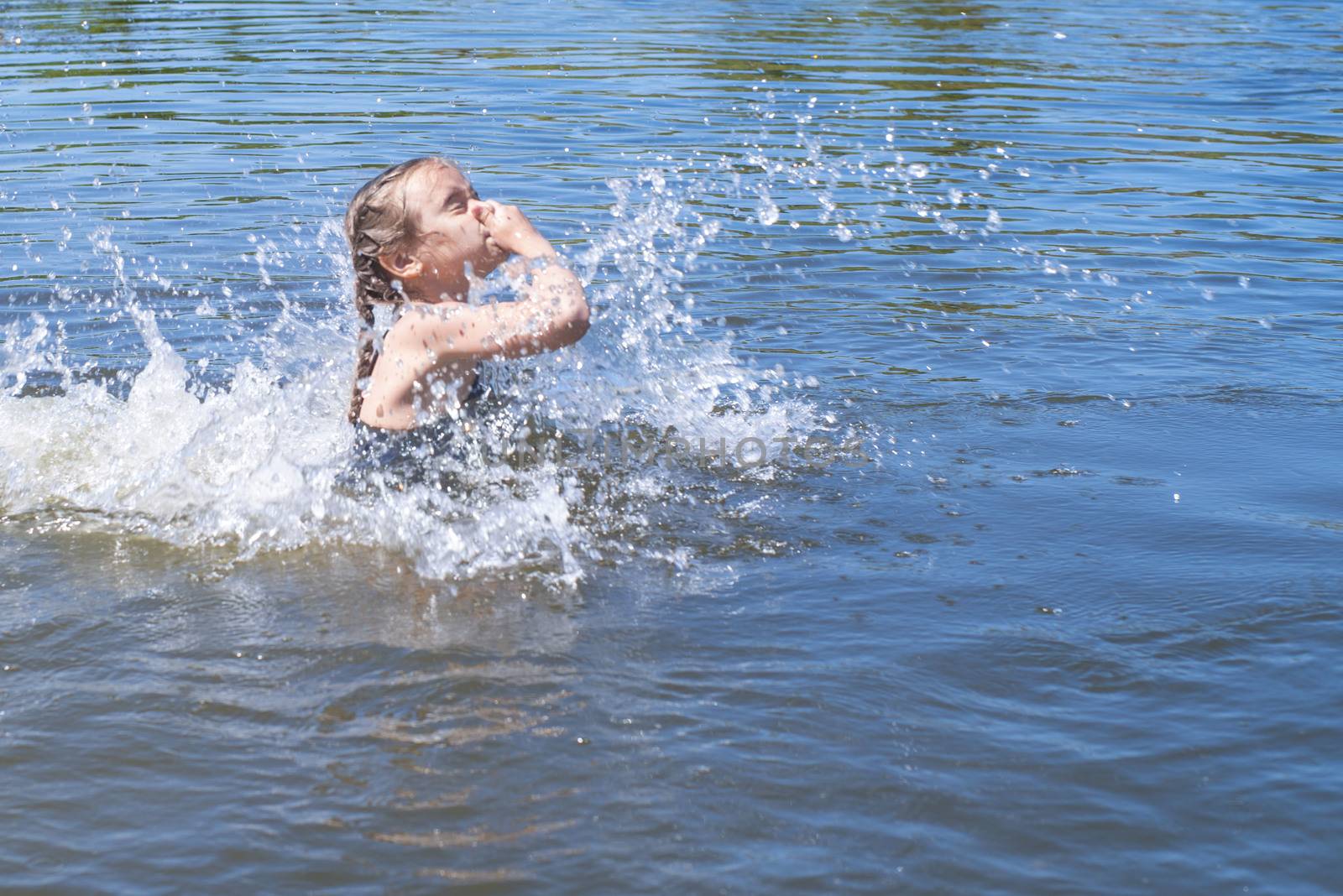 little girl running through the water with a splash . in her hands cloth.