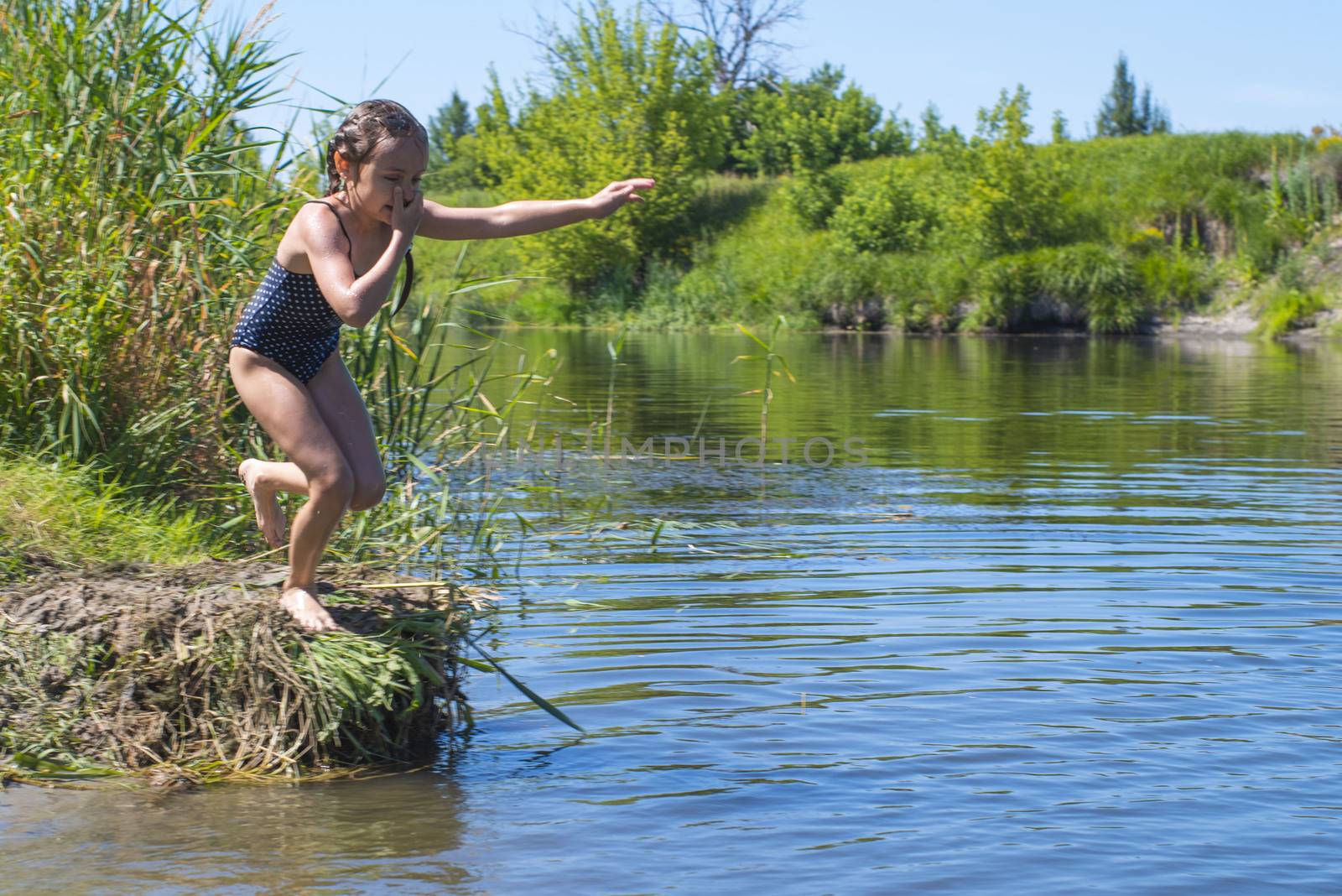 little girl running through the water with a splash . in her hands cloth.