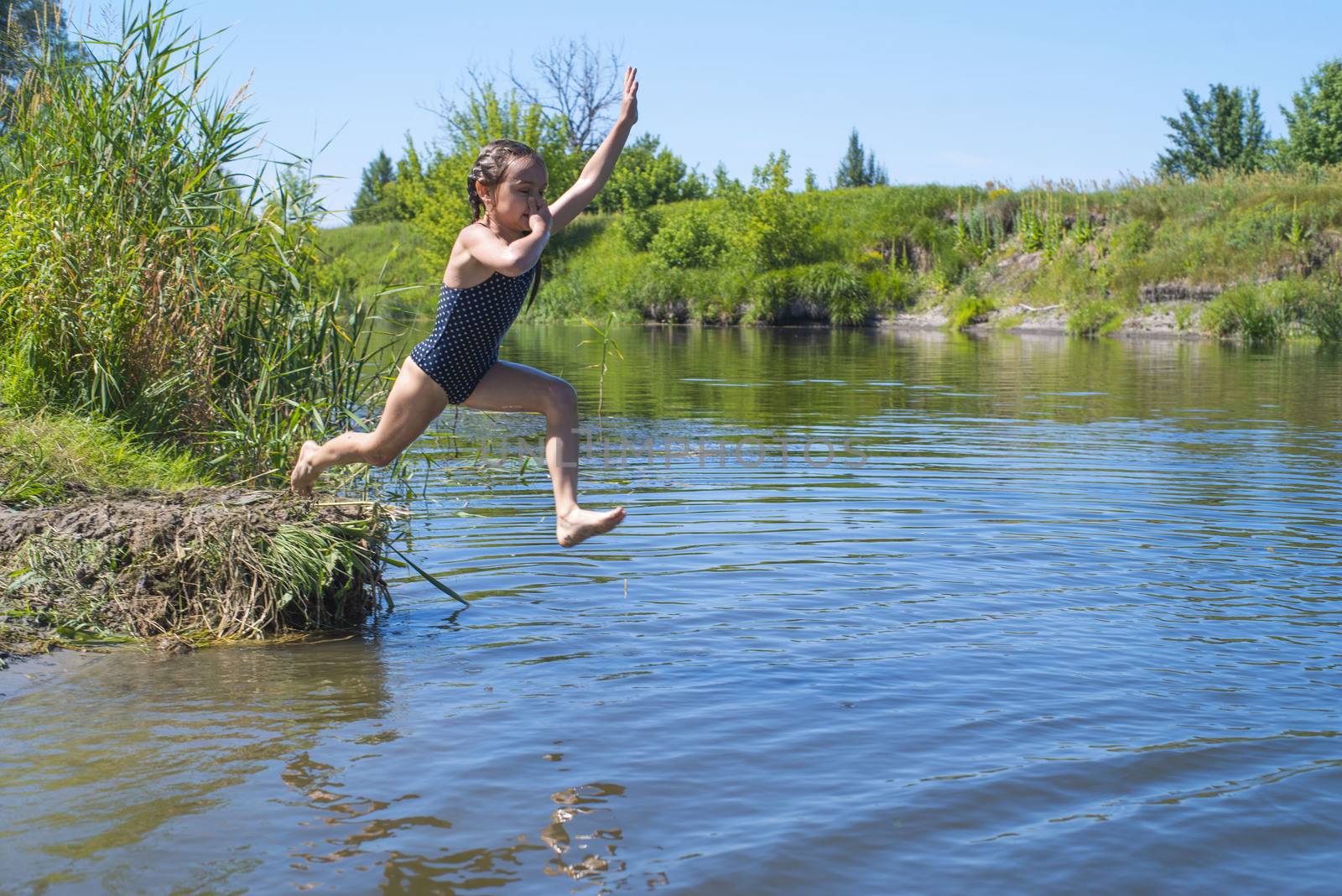 little girl running through the water with a splash . in her hands cloth.