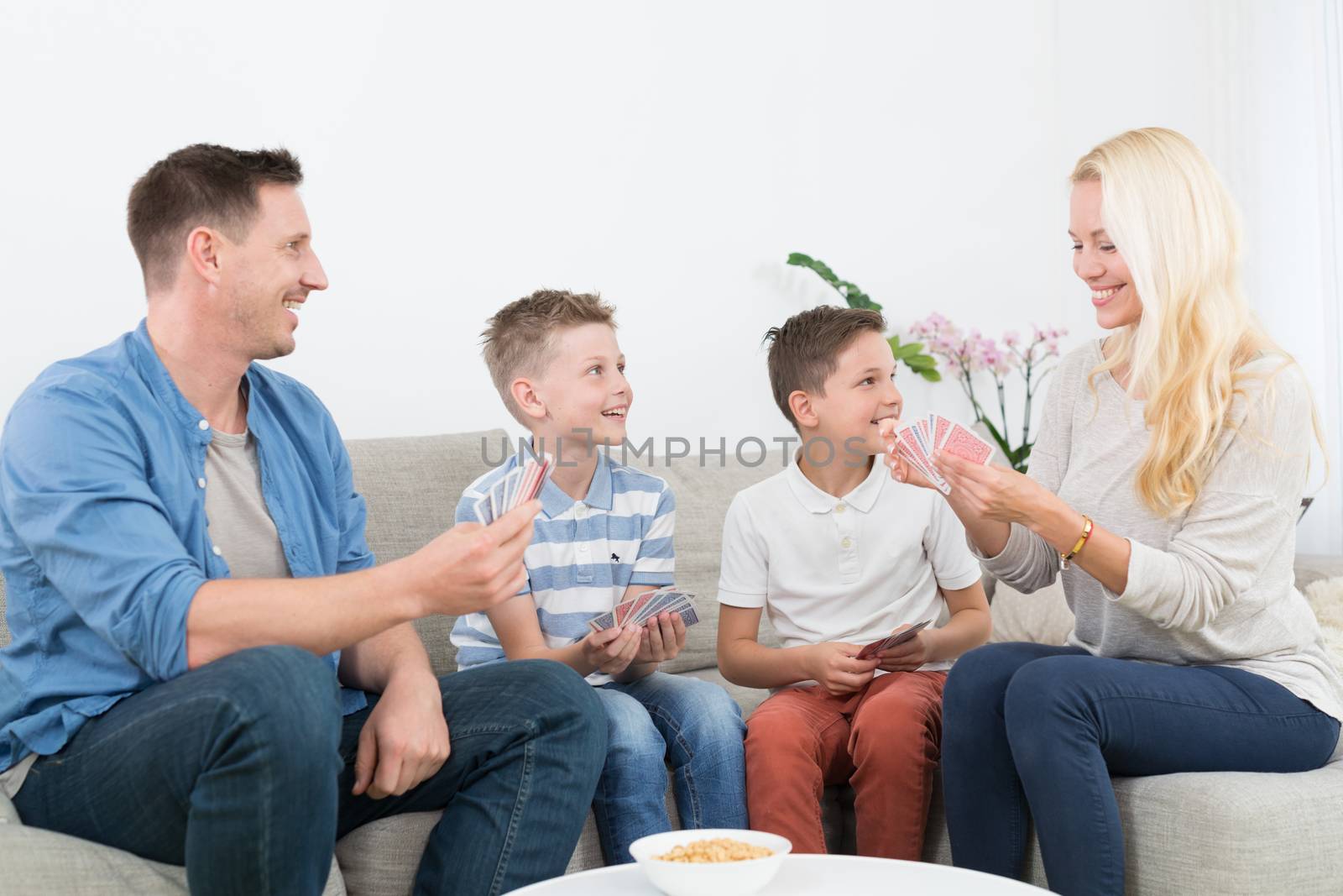 Happy young family playing card game at home. by kasto