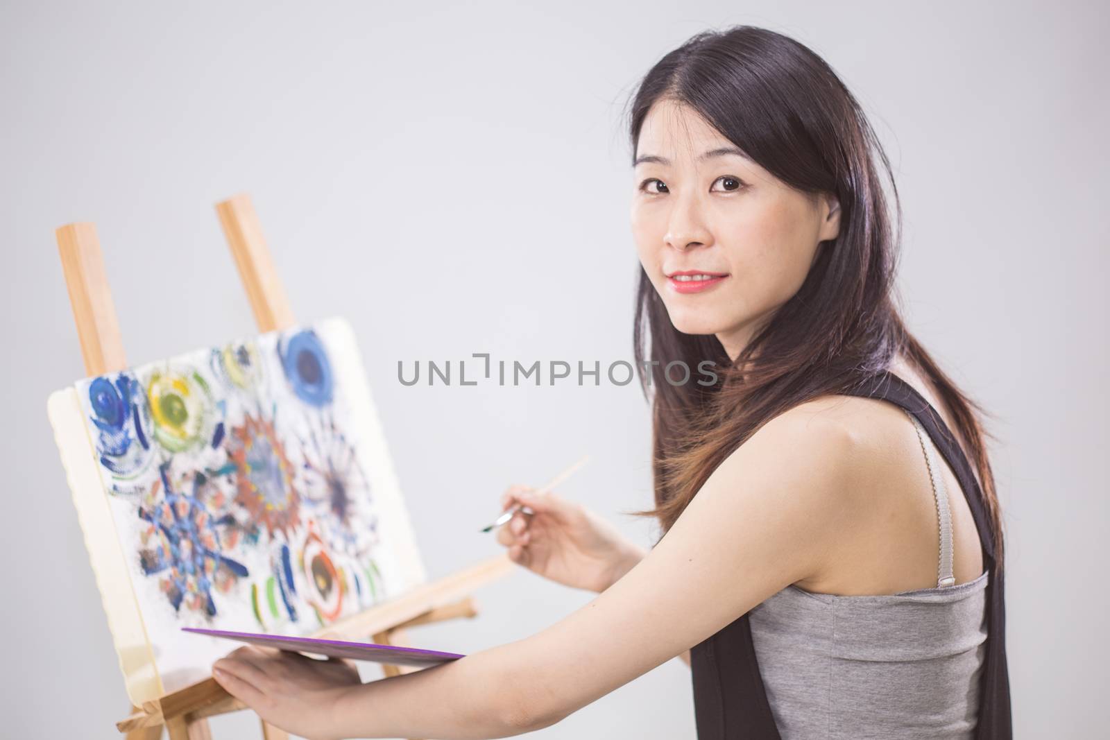 Artist painting on an easel, looking at camera