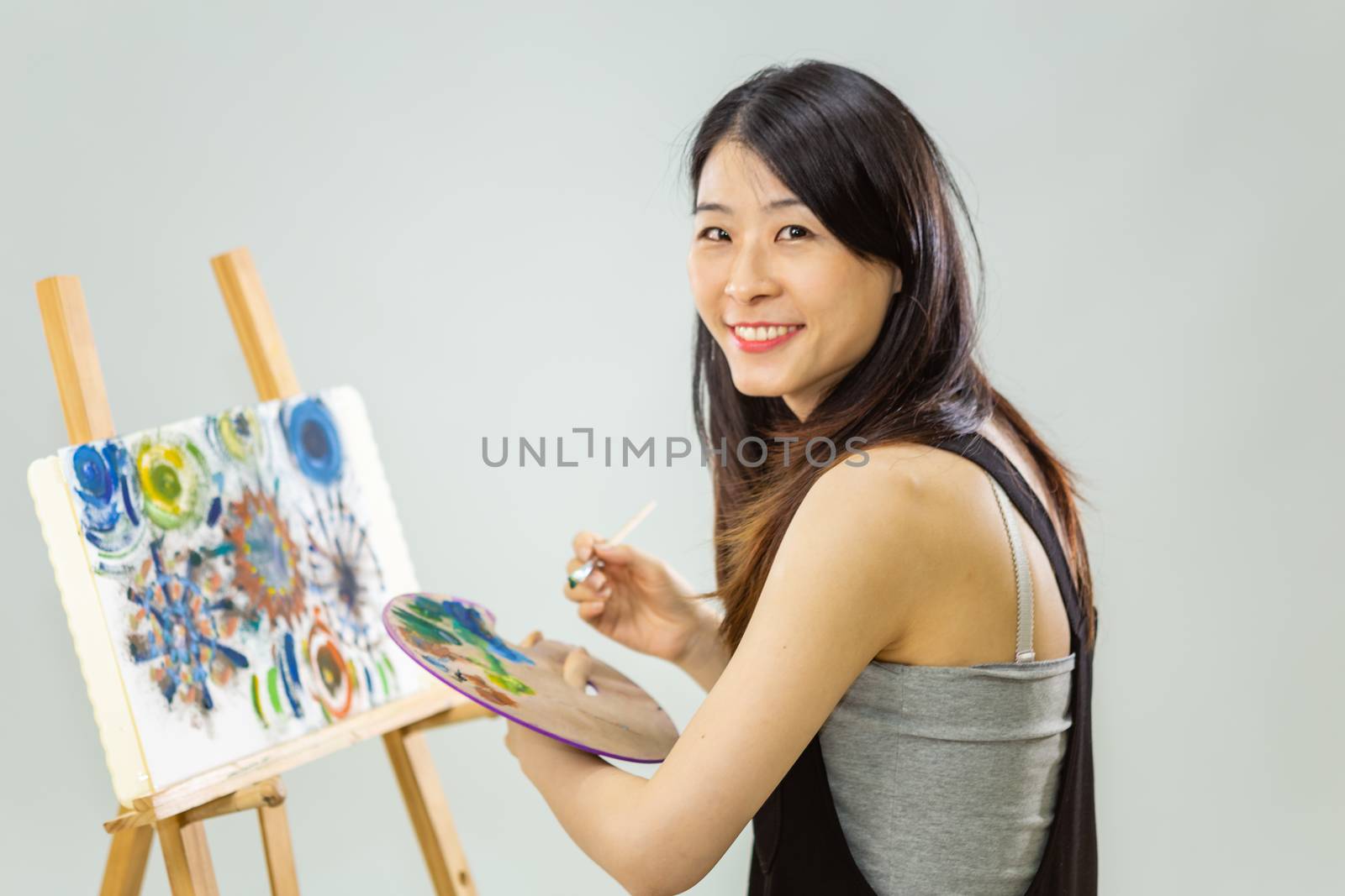 Artist painting on an easel, looking at camera