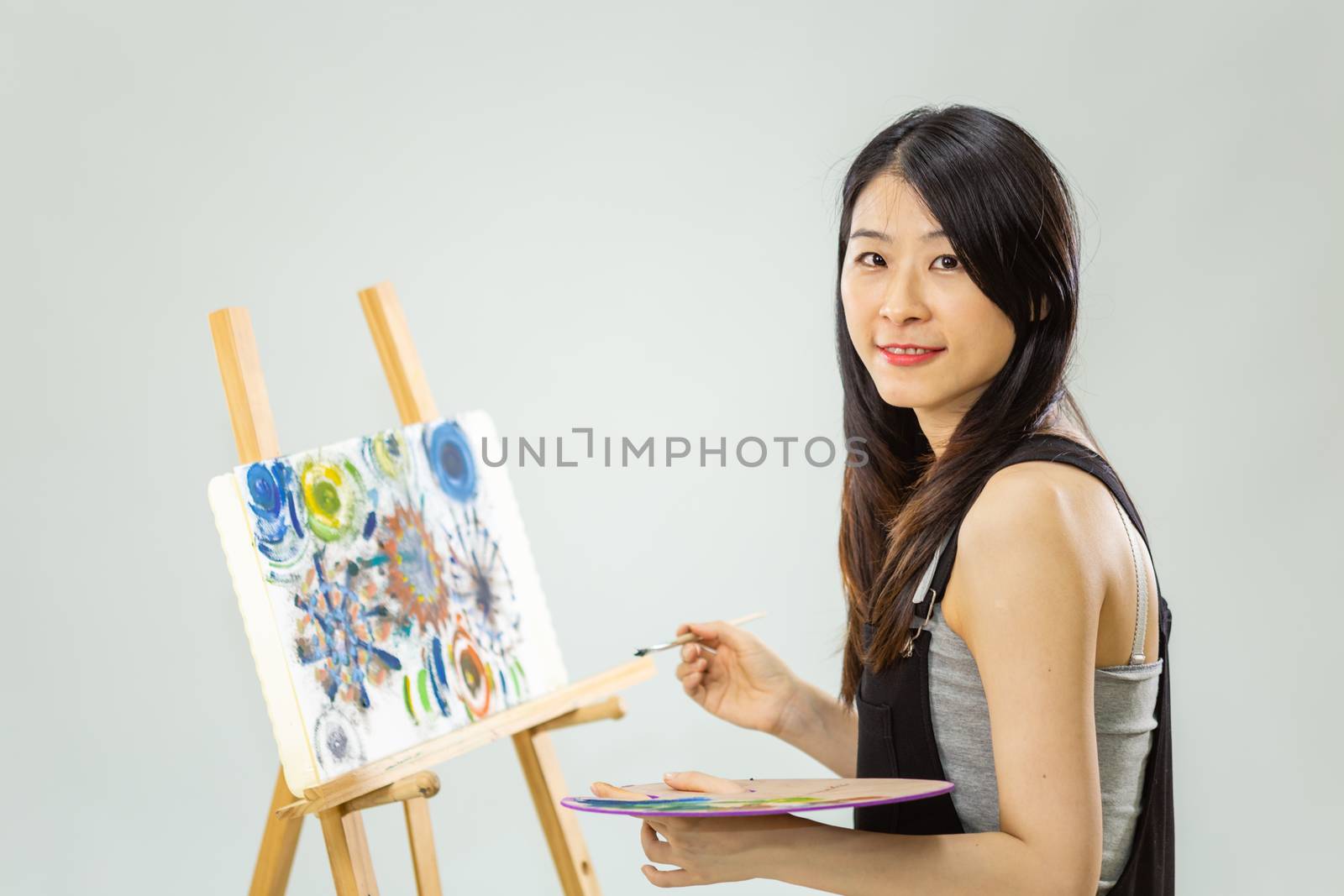 Artist painting on an easel, looking at camera