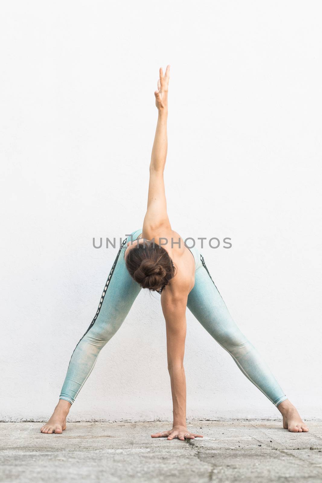 Fit sporty active girl in fashion sportswear doing yoga fitness exercise in front of gray wall, outdoor sports, urban style.