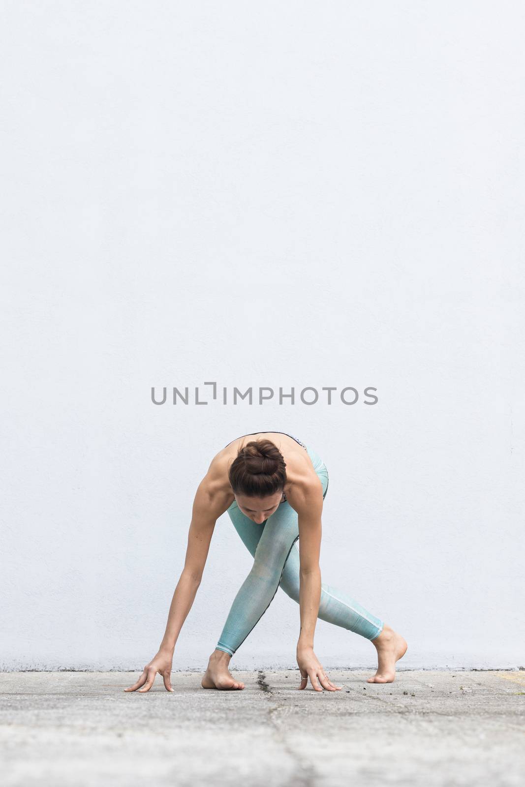 Fit sporty active girl in fashion sportswear doing yoga fitness exercise in front of gray wall, outdoor sports, urban style by kasto