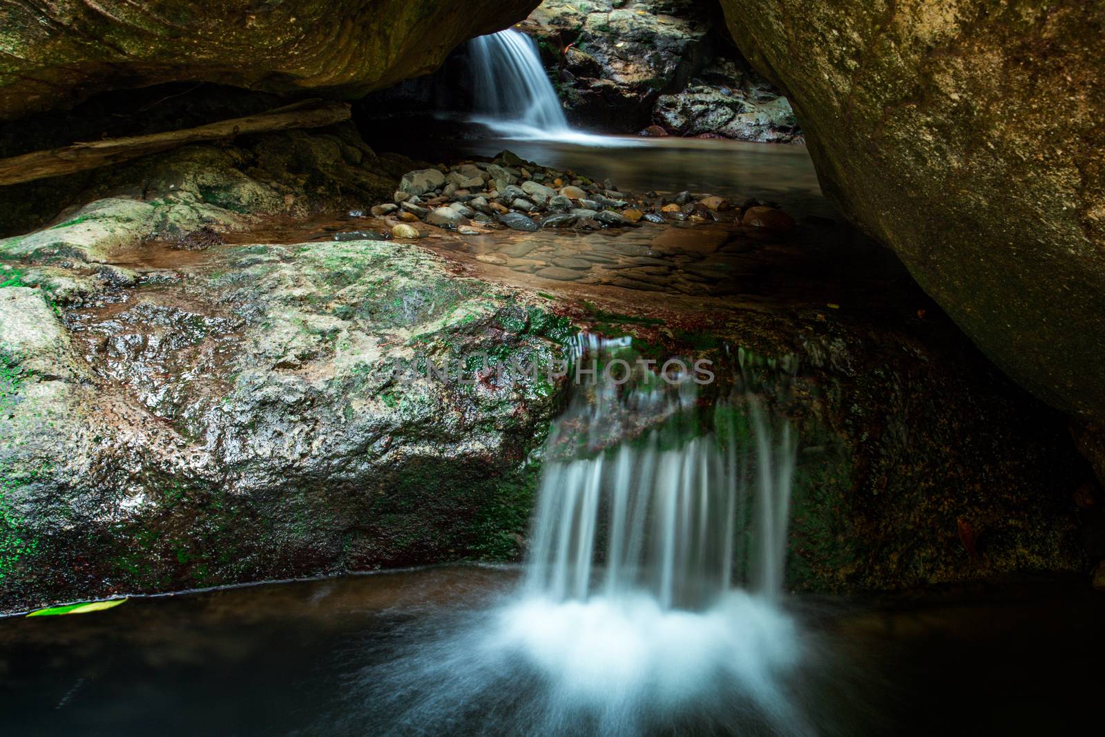 The flow through of a waterfall through a large cavern of boulders and rocks as it erodes its path down the mountain.