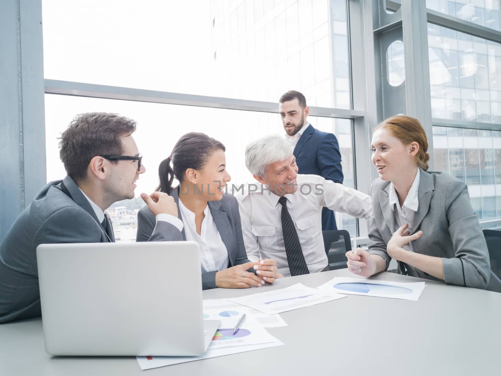 Business team sitting by the table with laptop and documents in office