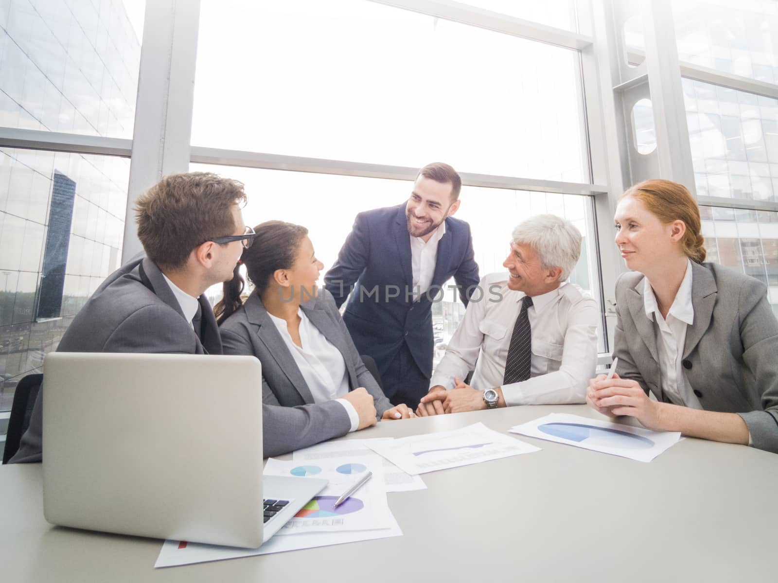 Business team sitting by the table with laptop and documents in office