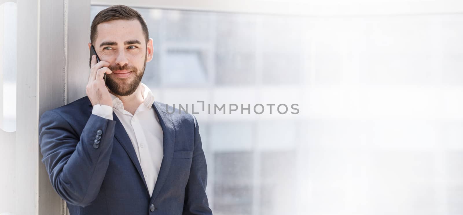 Businessman talking on cell phone in office , white copy space for text content