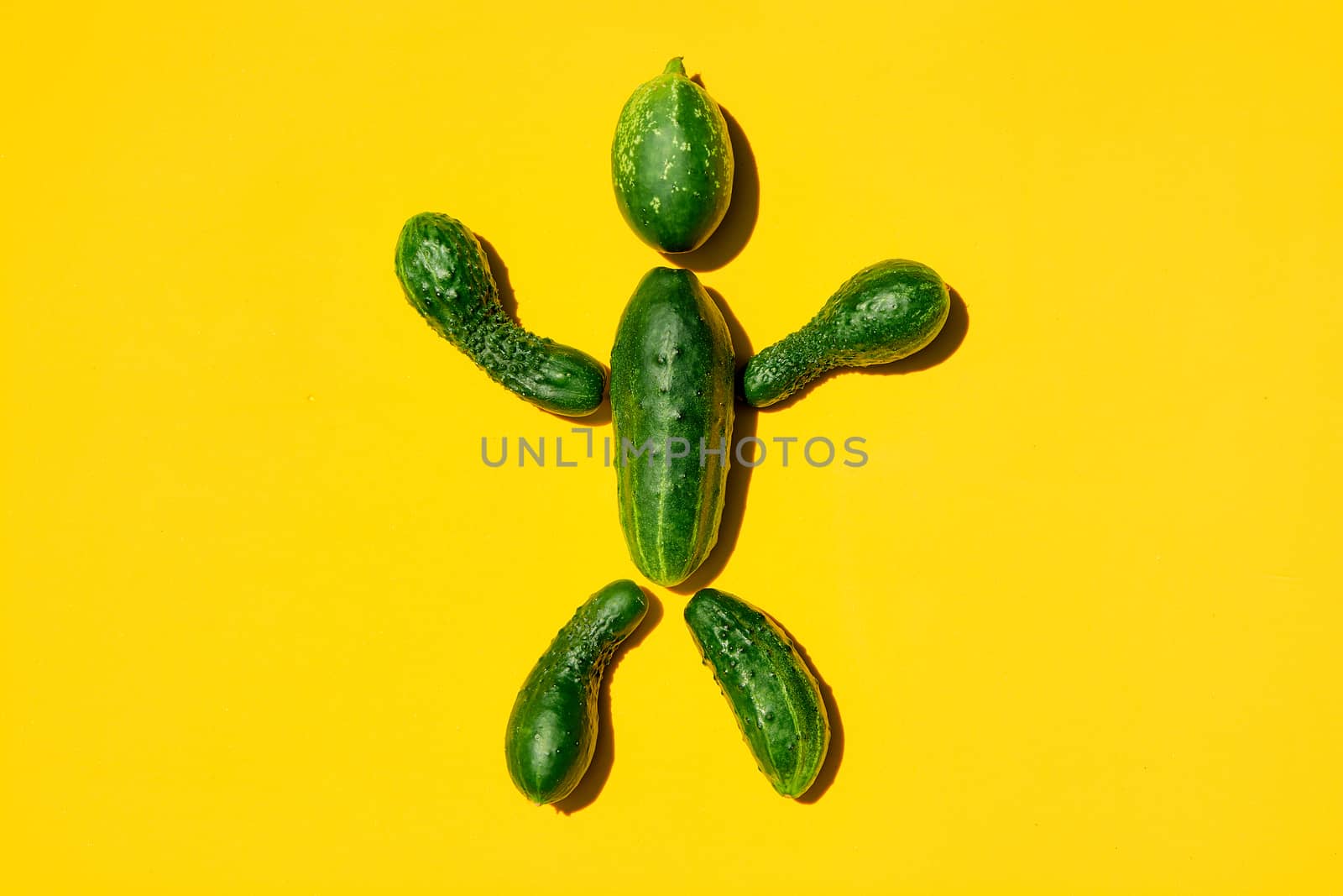 Cucumber man on a yellow background. Figure of man made from cucumbers. by nixrenas