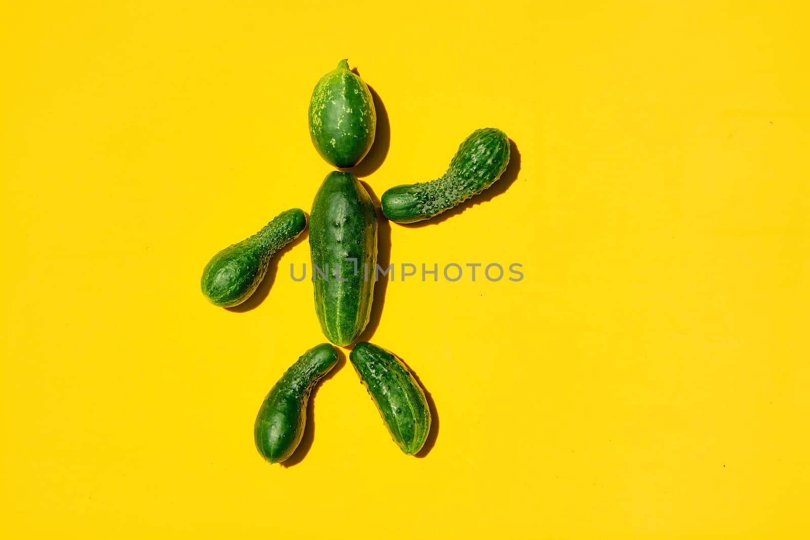 Cucumber man on a yellow background. Figure of man made from cucumbers. by nixrenas