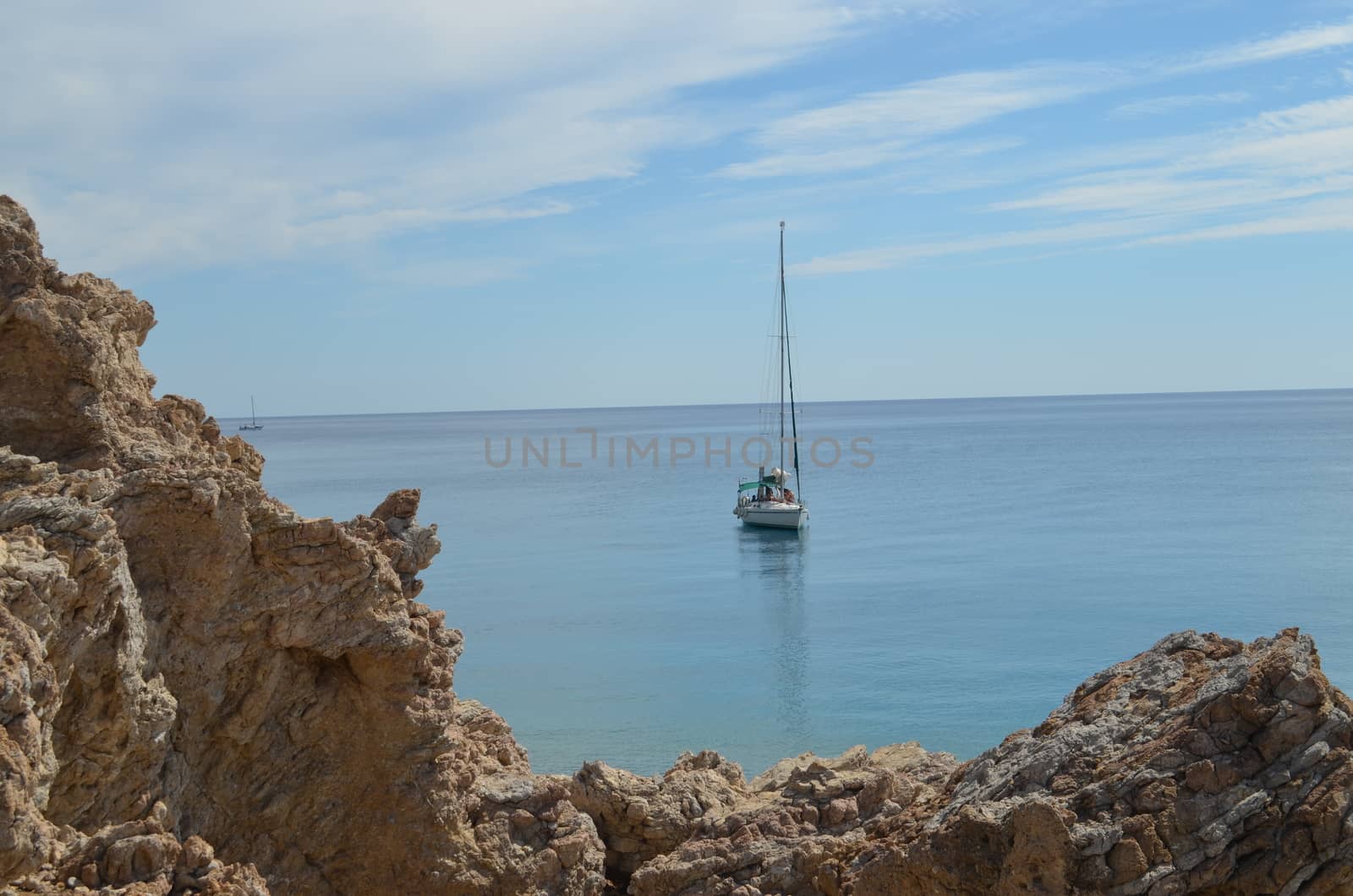 Sailboat in The Mediterranean Sea In Calm Water With a Rock in The Fore Ground