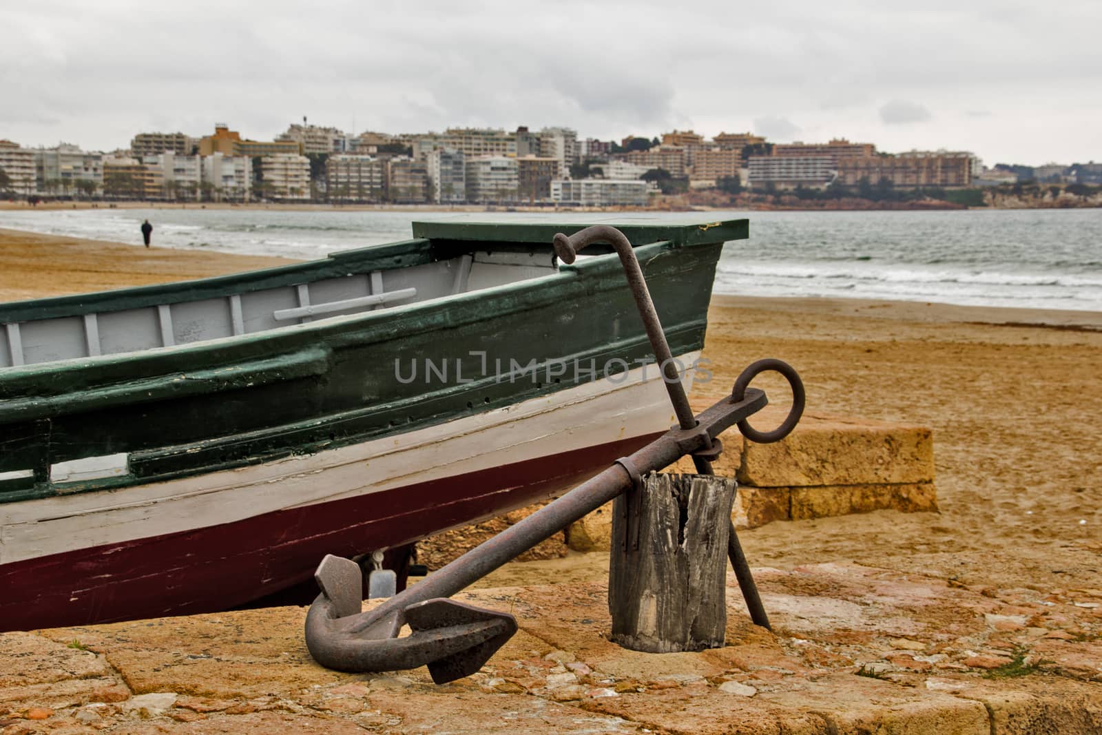 Fishing boat anchored in the sand in Salou, Catalonia, at the seaside and a buildings background