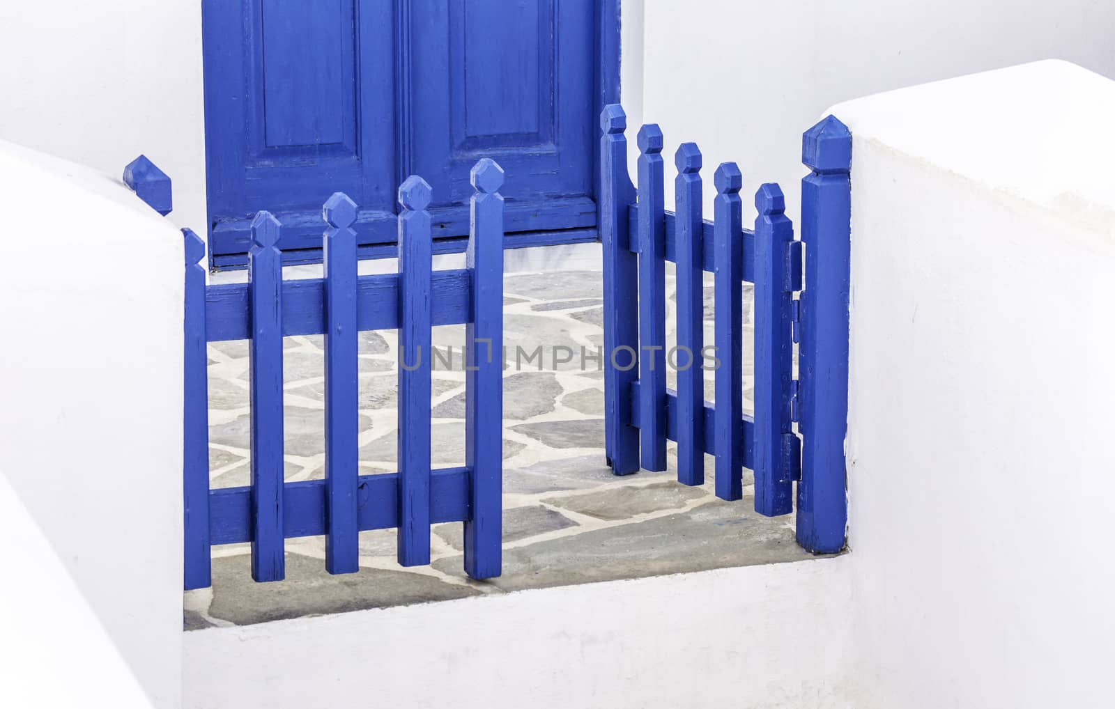 Blue wooden gate and door in a traditional Greek Cycladic house in a Greek island on the Aegean sea on a nice, hot summer day during holidays
