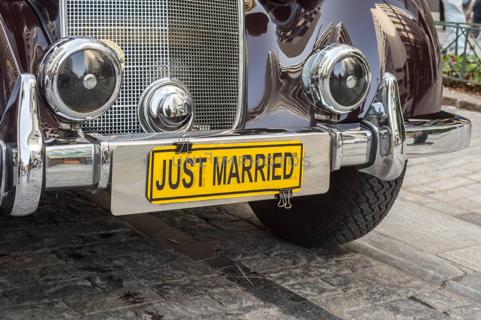 One classical, polished old car used for transportation of wedding with a yellow "JUST MARRIED" license plate - street photography