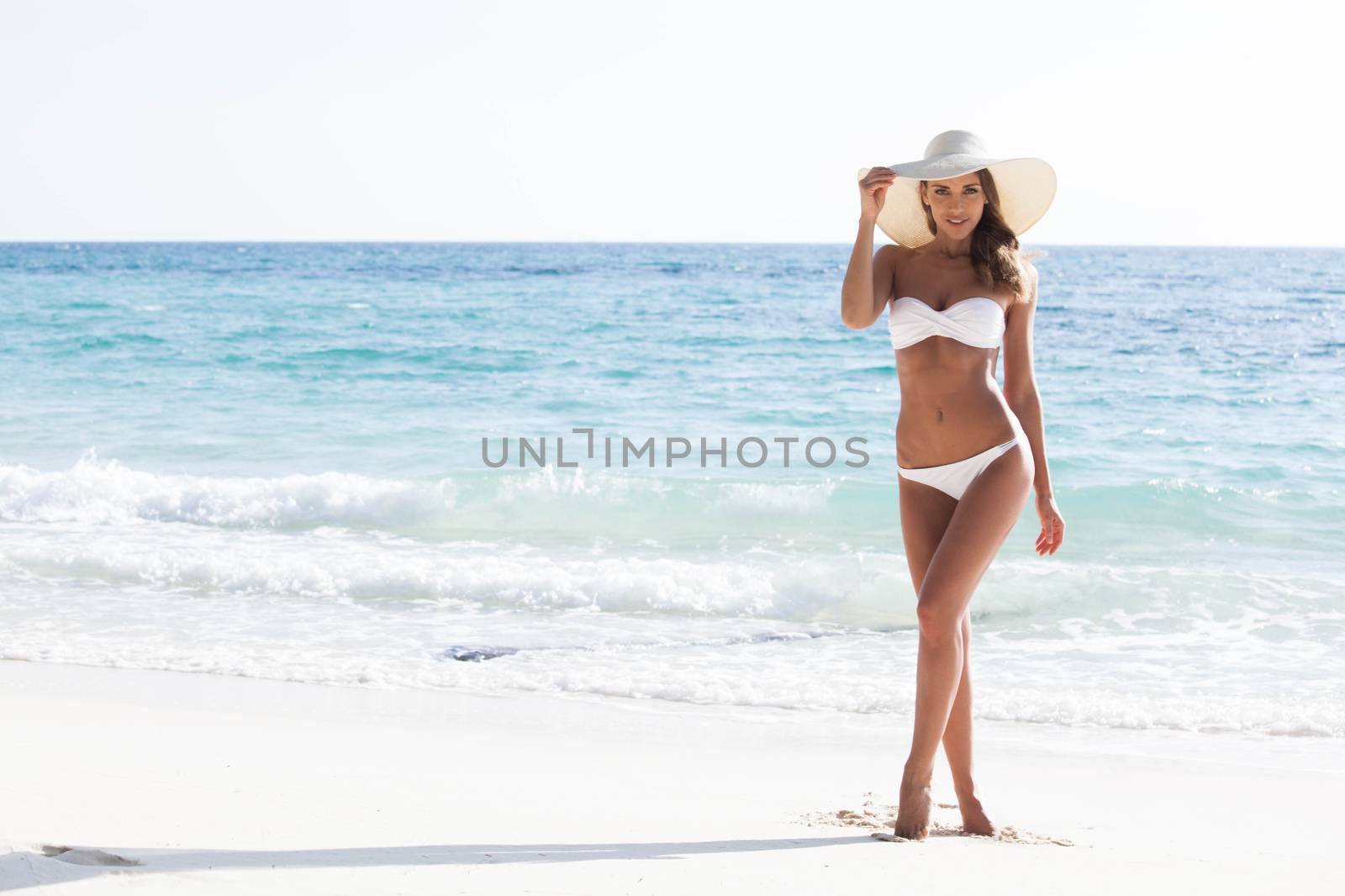 Woman in bikini and sunhat on the beach