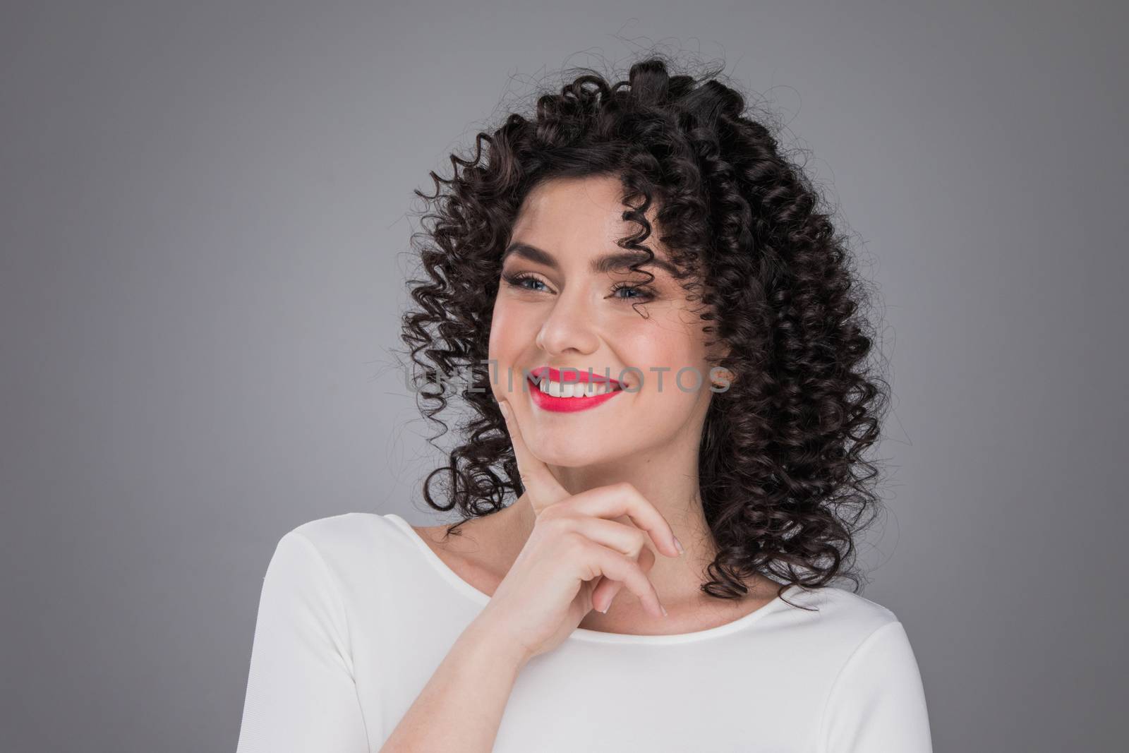 Portrait of beautiful smiling woman with curly hair, gray background