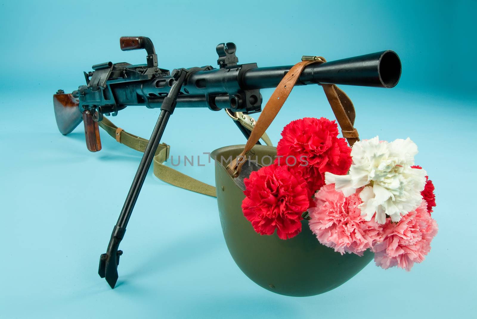 Machine gun and flowers in an army helmet