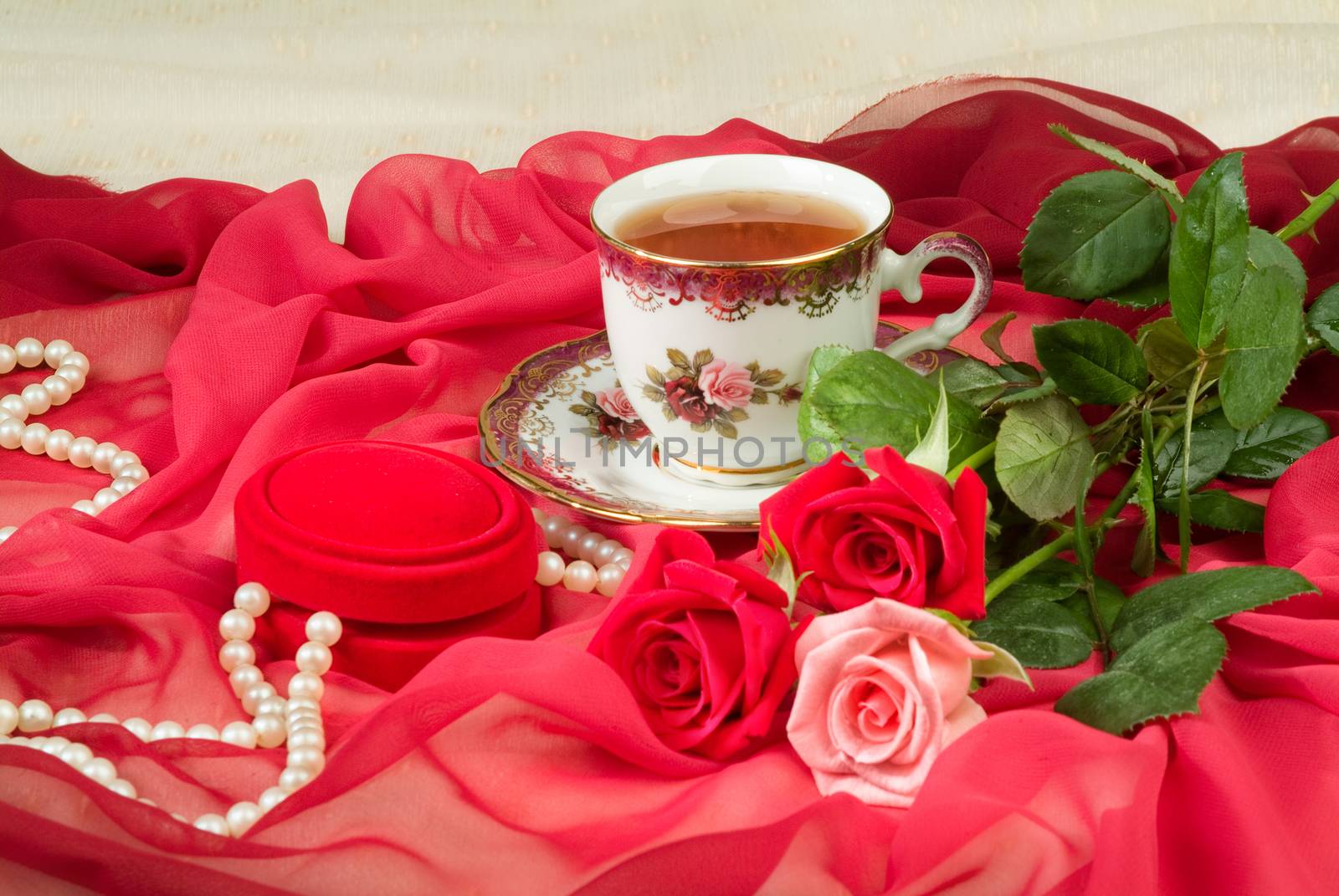 Cup of tea and bouquet of roses on a fabric background