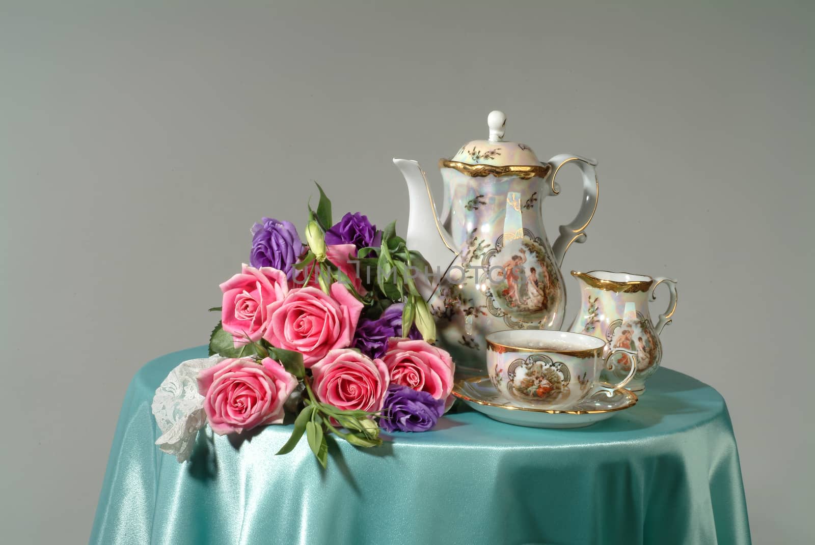 Tea set and bouquet of flowers on a studio background