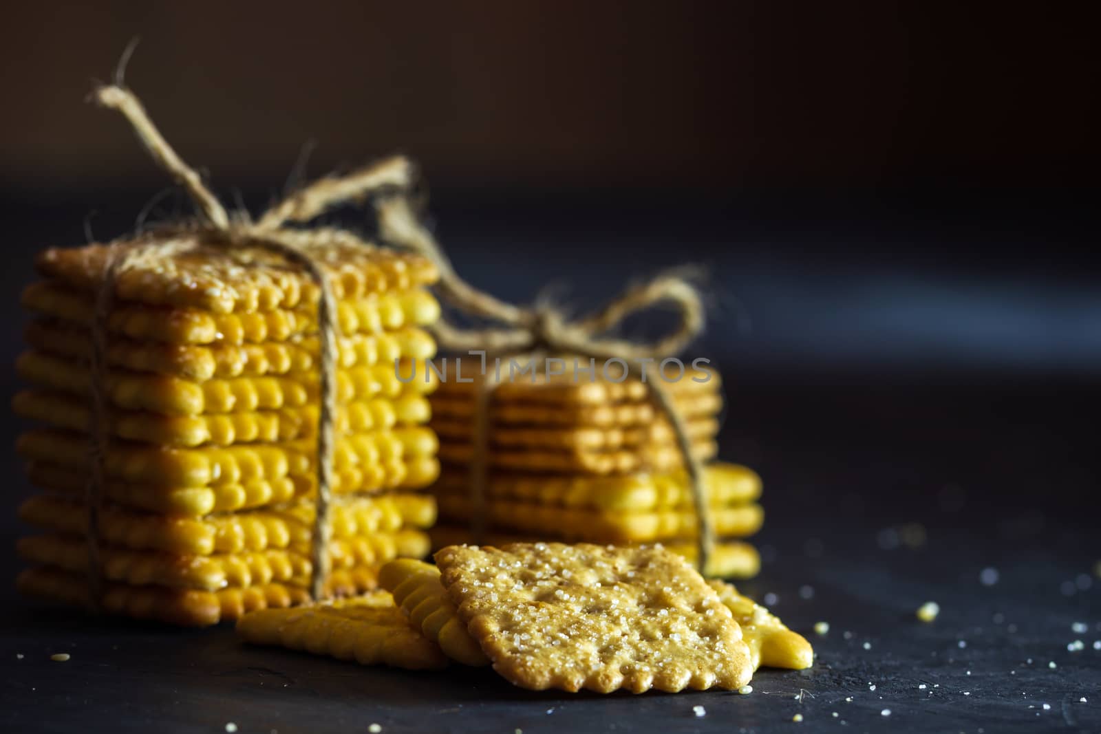 Crackers are tied with hemp rope on table in dark background. by SaitanSainam