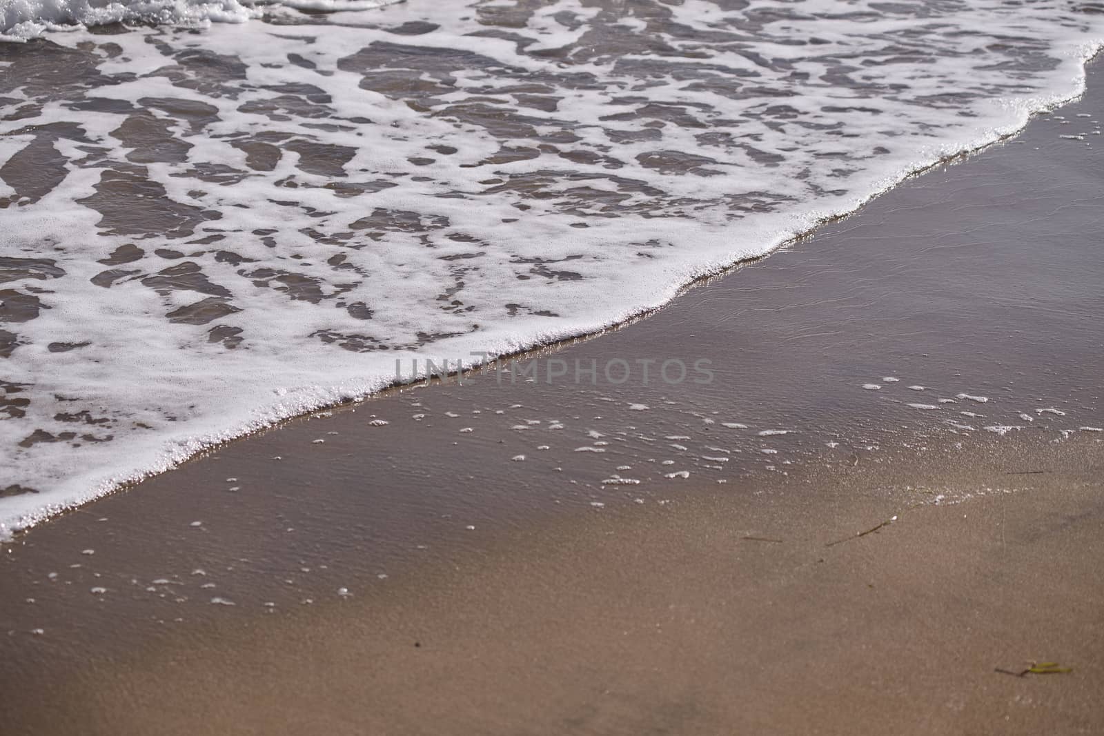 Sea waves on shoreline on orange sand