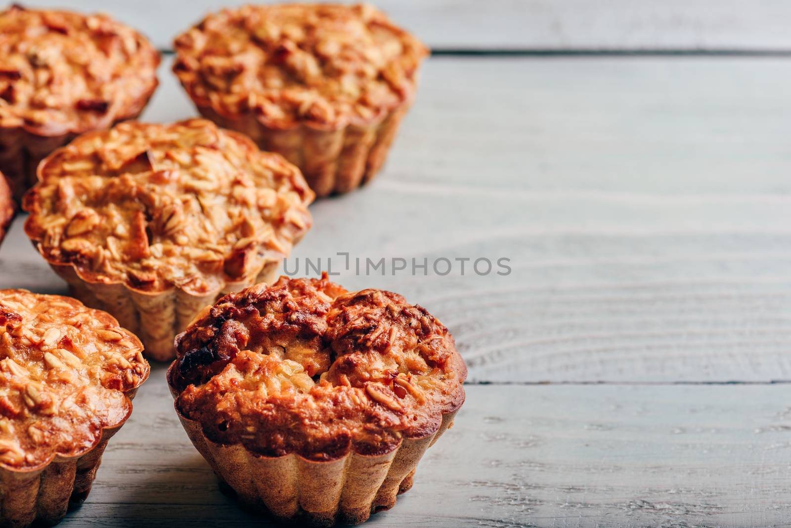 Cooked oatmeal muffins on light wooden background.