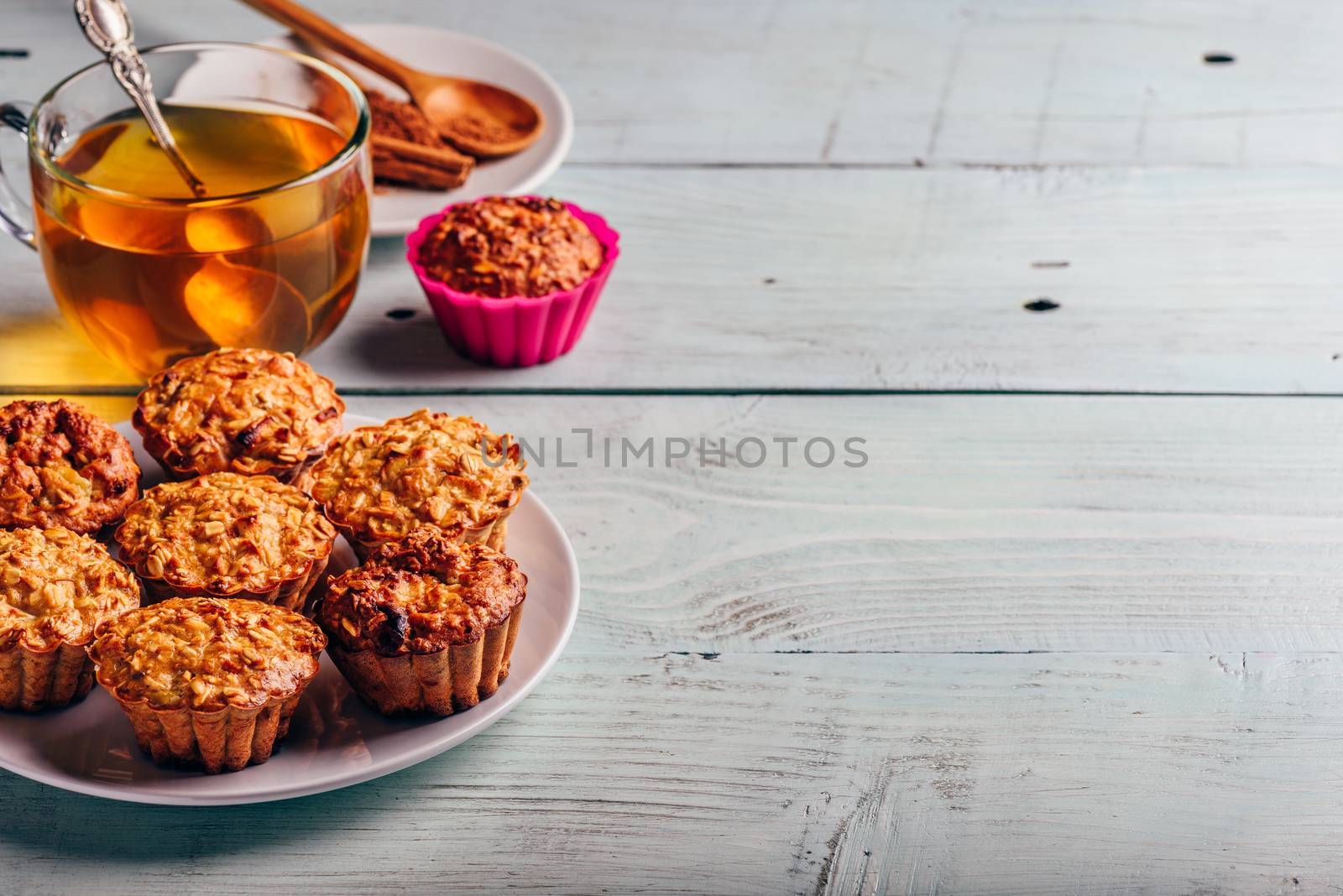 Healthy Dessert. Oatmeal muffins with cup of green tea over light wooden background. Copy Space.